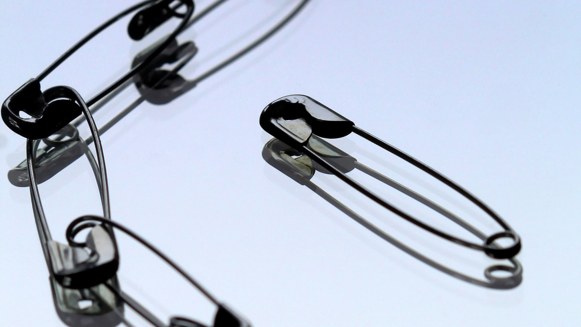 silver safety pin on white paper