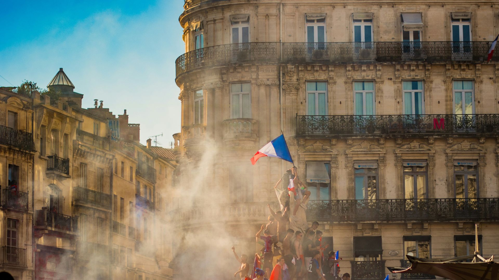 people waving flag of France near building