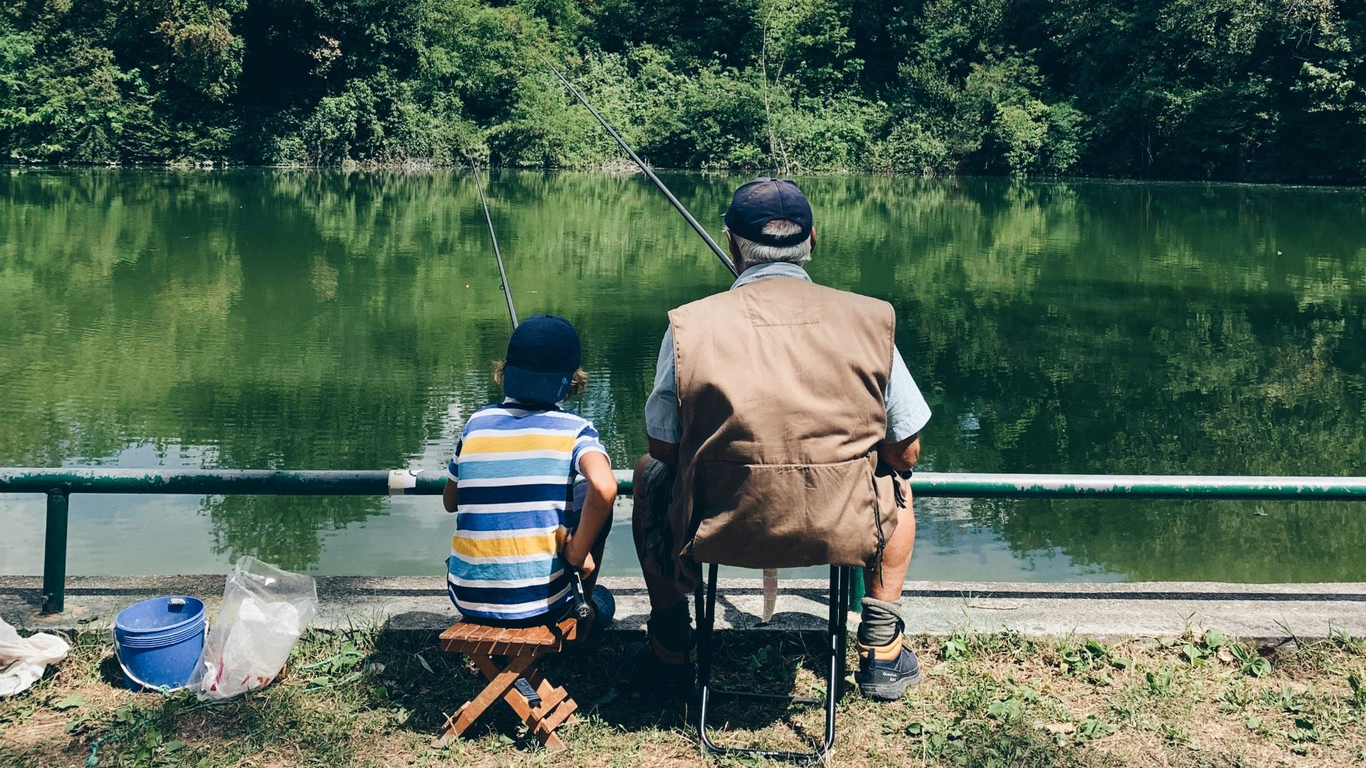 man in black shirt sitting on chair near lake during daytime