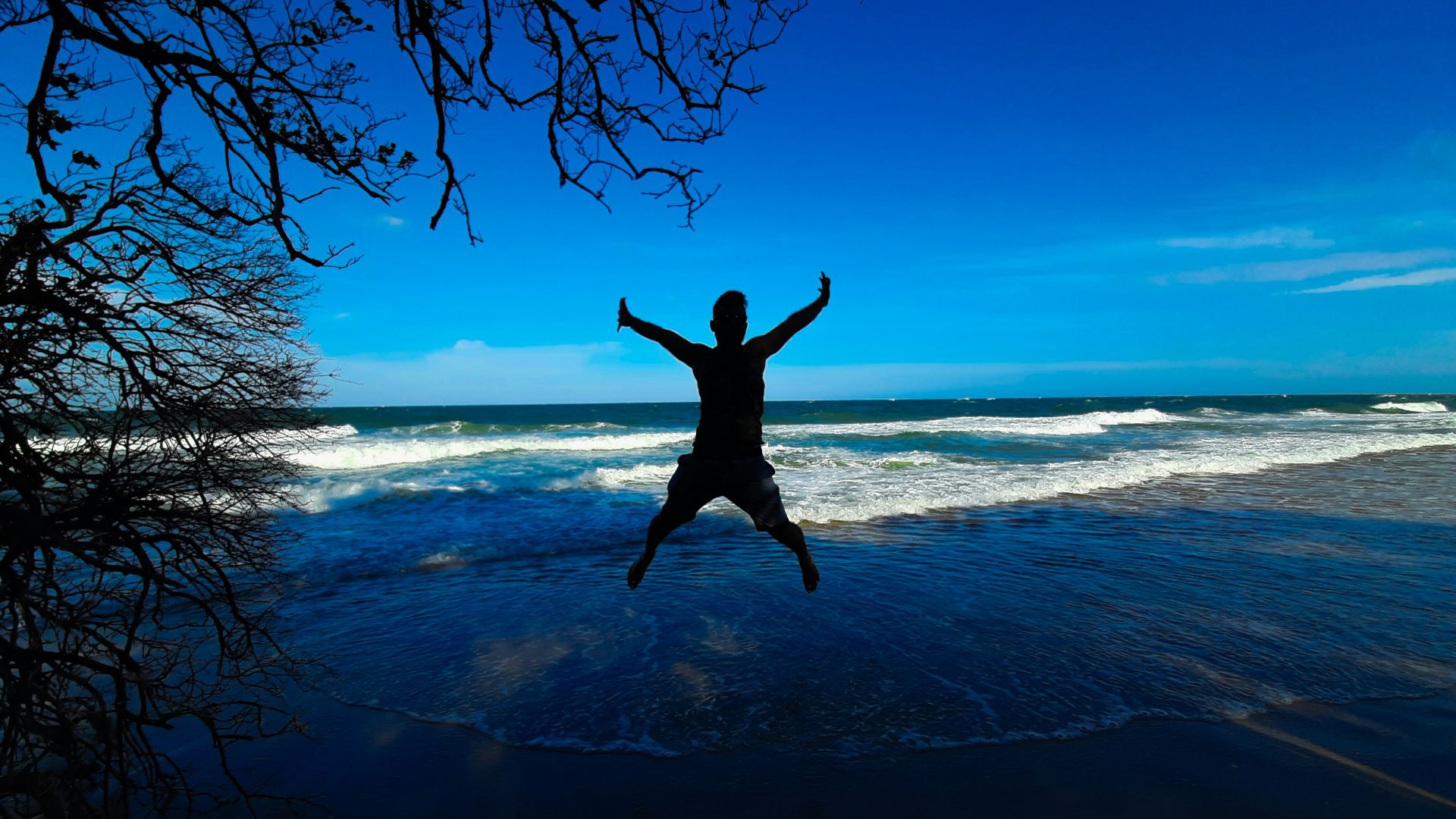 man jumping on the beach during daytime