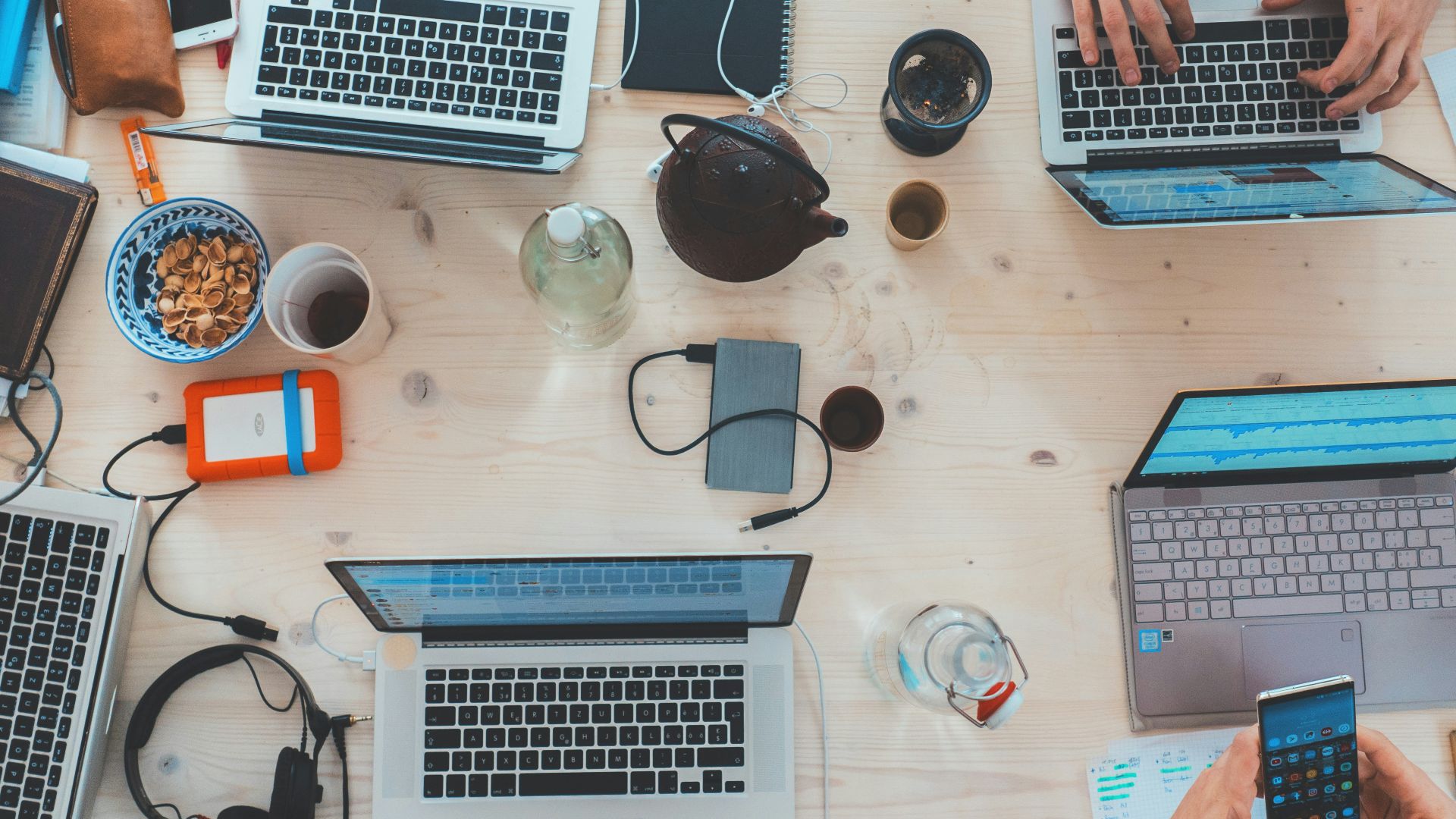 people sitting down near table with assorted laptop computers
