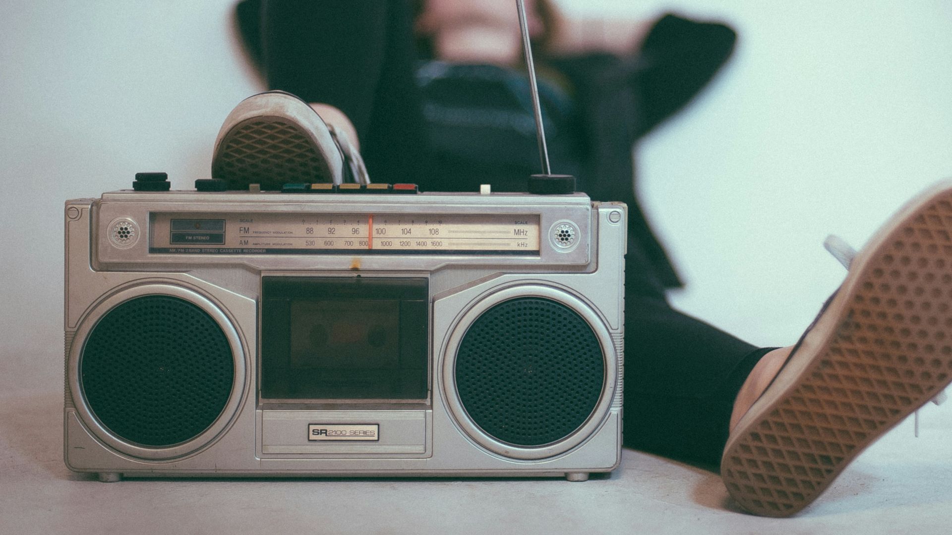 woman laying on bed near gray radio