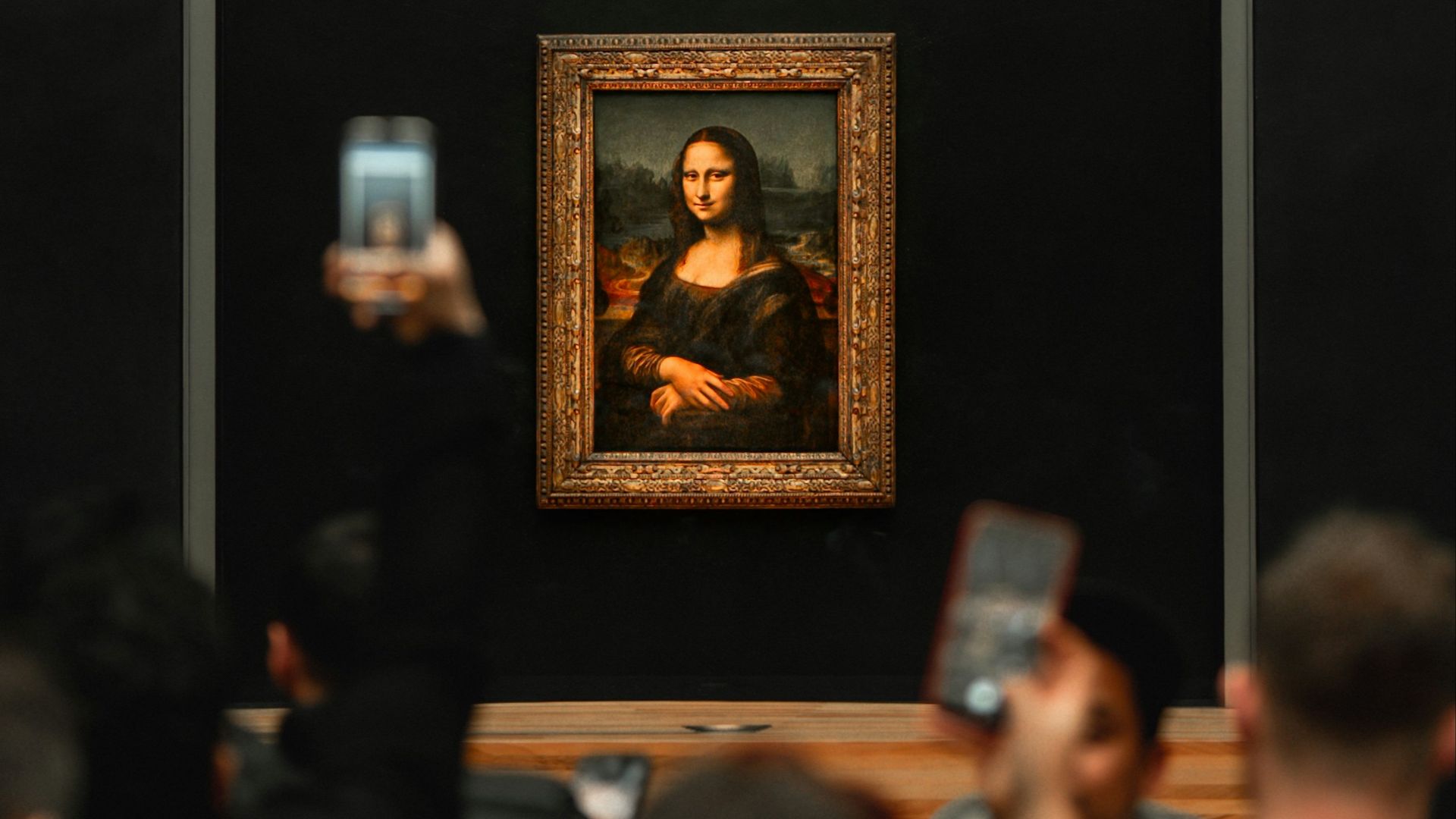 A group of people taking pictures of a painting