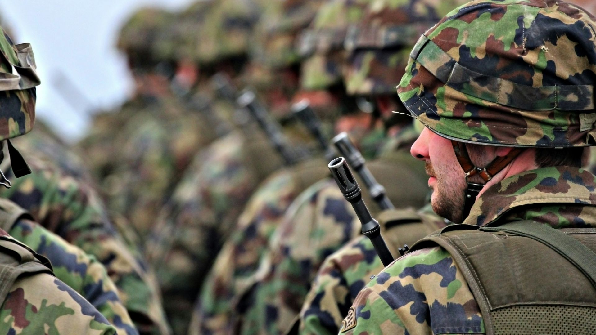 man in green and brown camouflage uniform holding black rifle