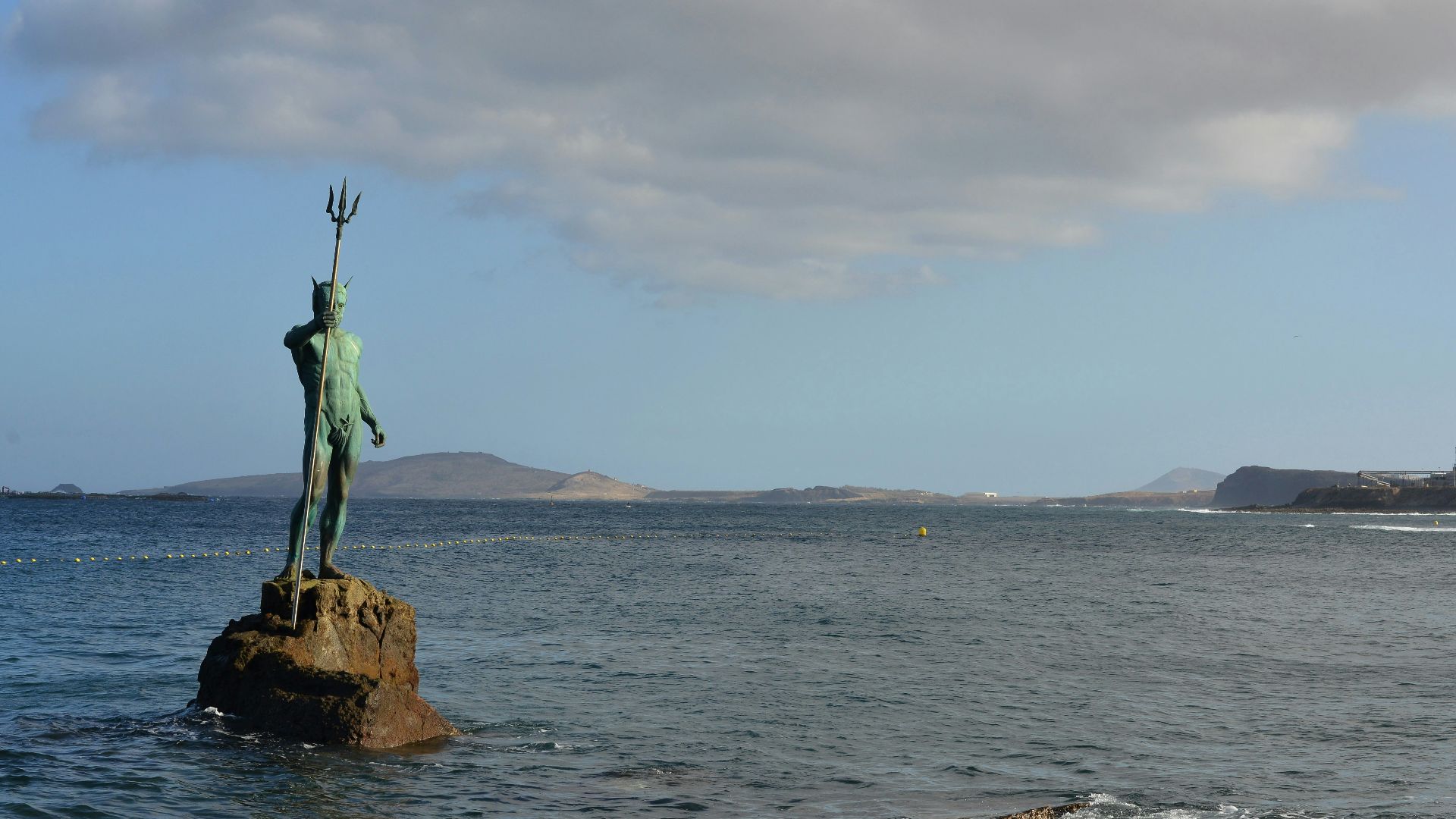 person in green shirt standing on brown rock formation near body of water during daytime