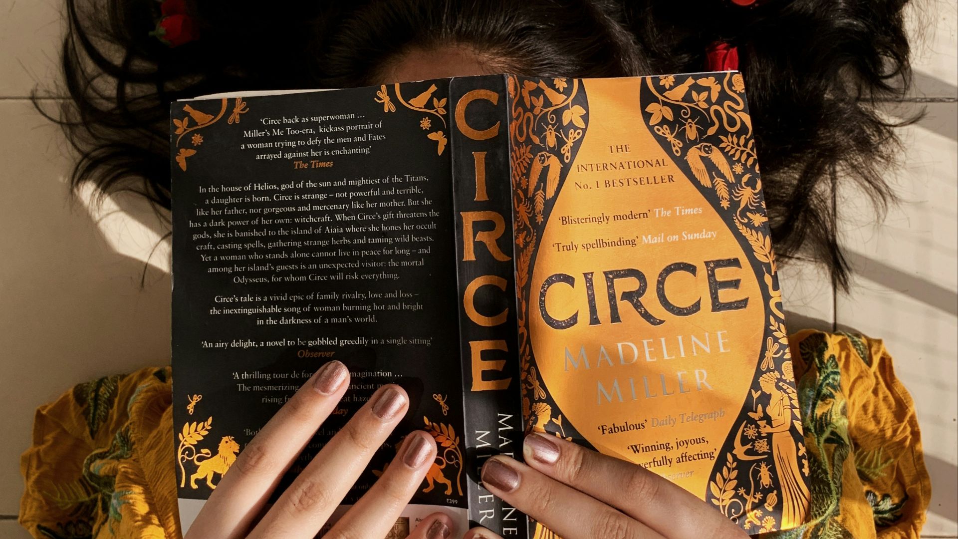 woman in yellow and brown floral dress holding black and brown book