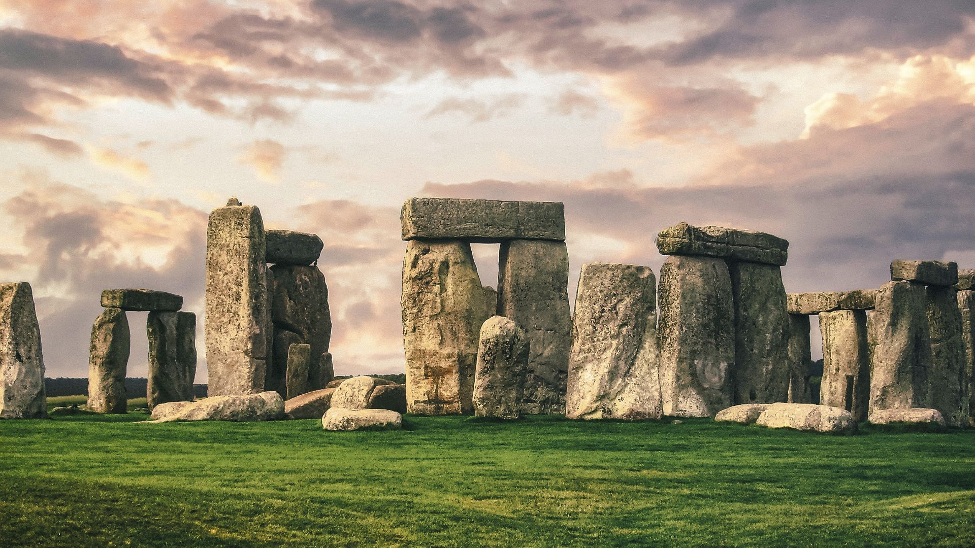 gray rock formation on green grass field under gray cloudy sky