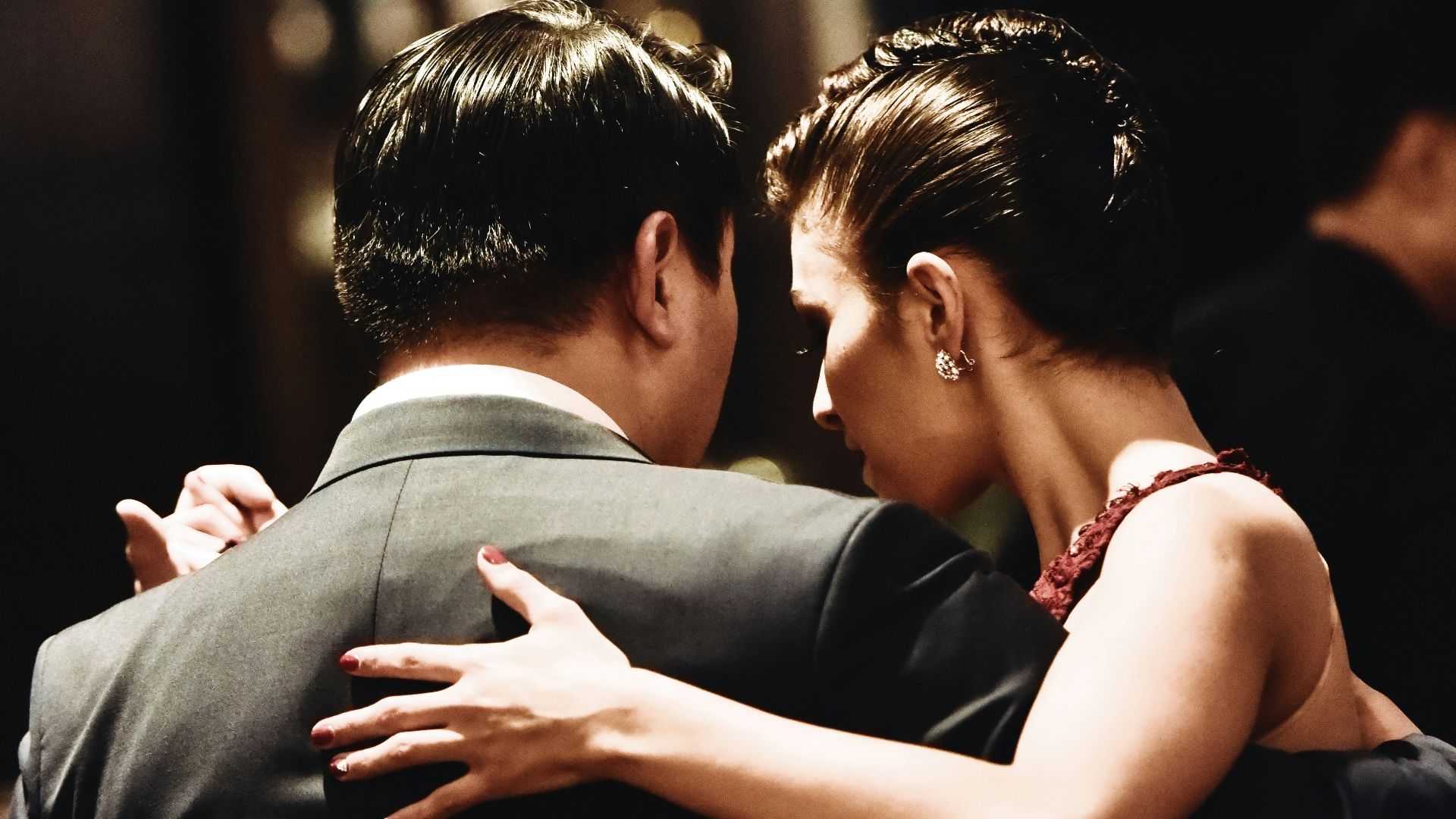 man wearing balck suit jacket and woman wearing red dress dancing