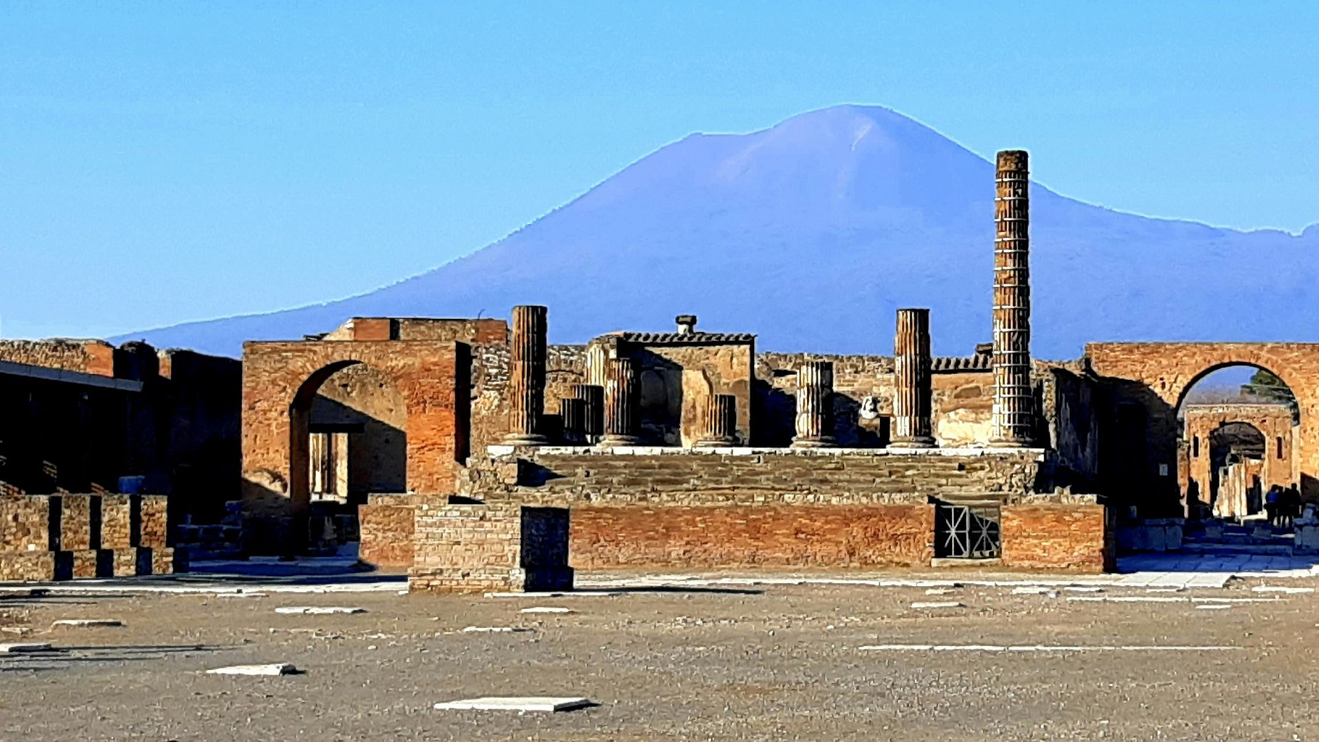 brown concrete building near mountain under blue sky during daytime