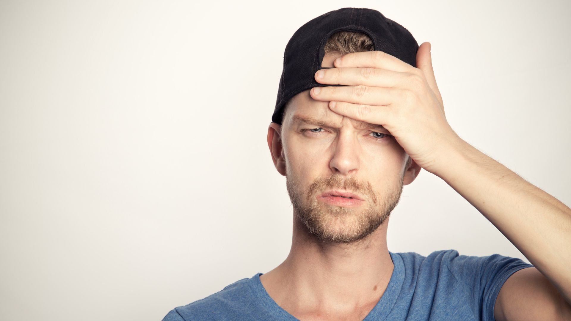 man in blue crew neck shirt covering his face