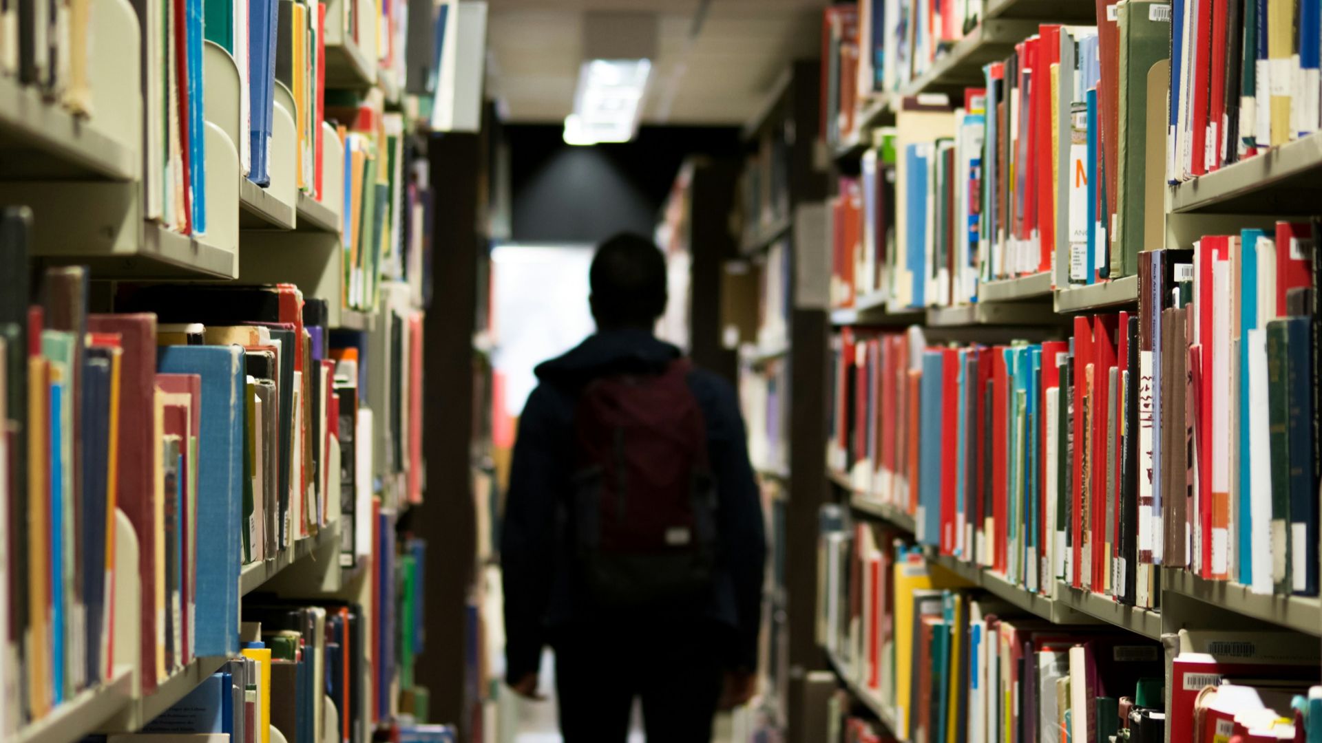 man with backpack beside a books