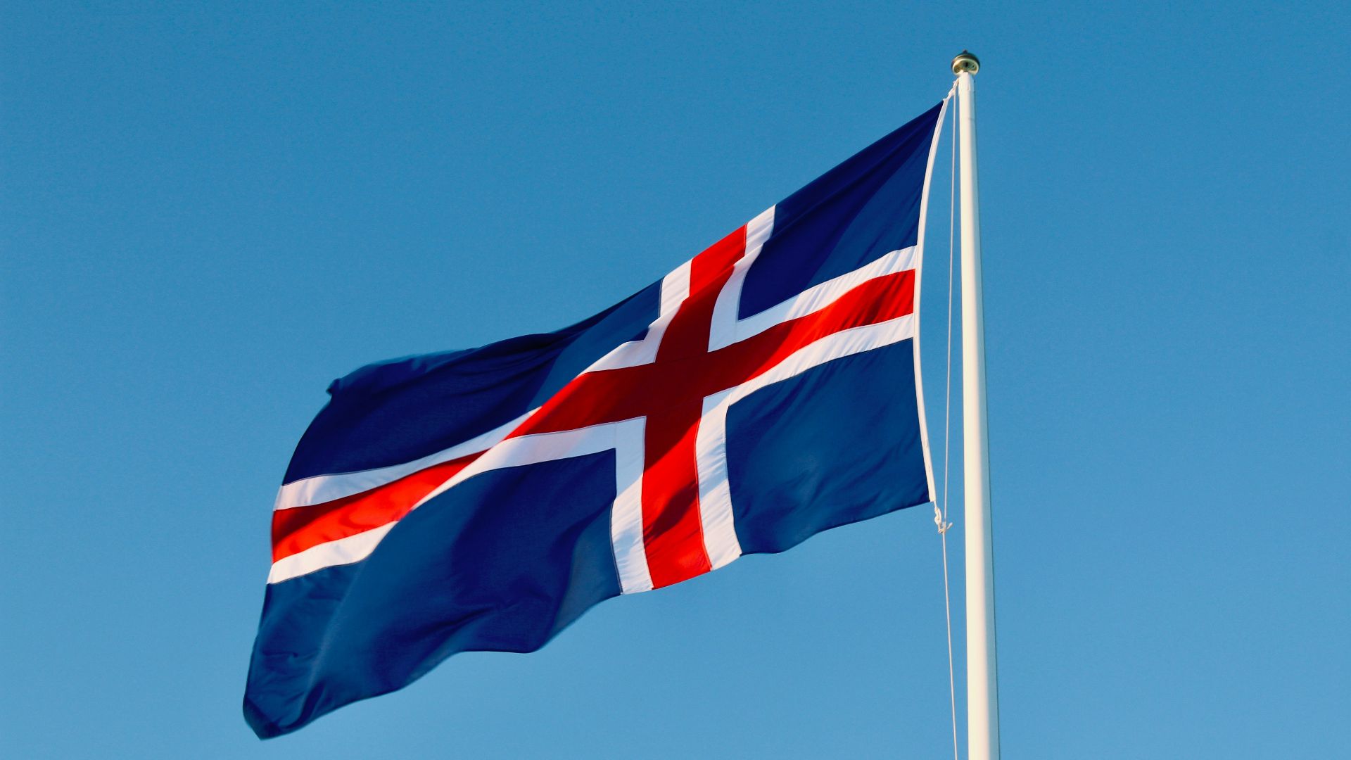 a flag flying in the wind with a blue sky in the background
