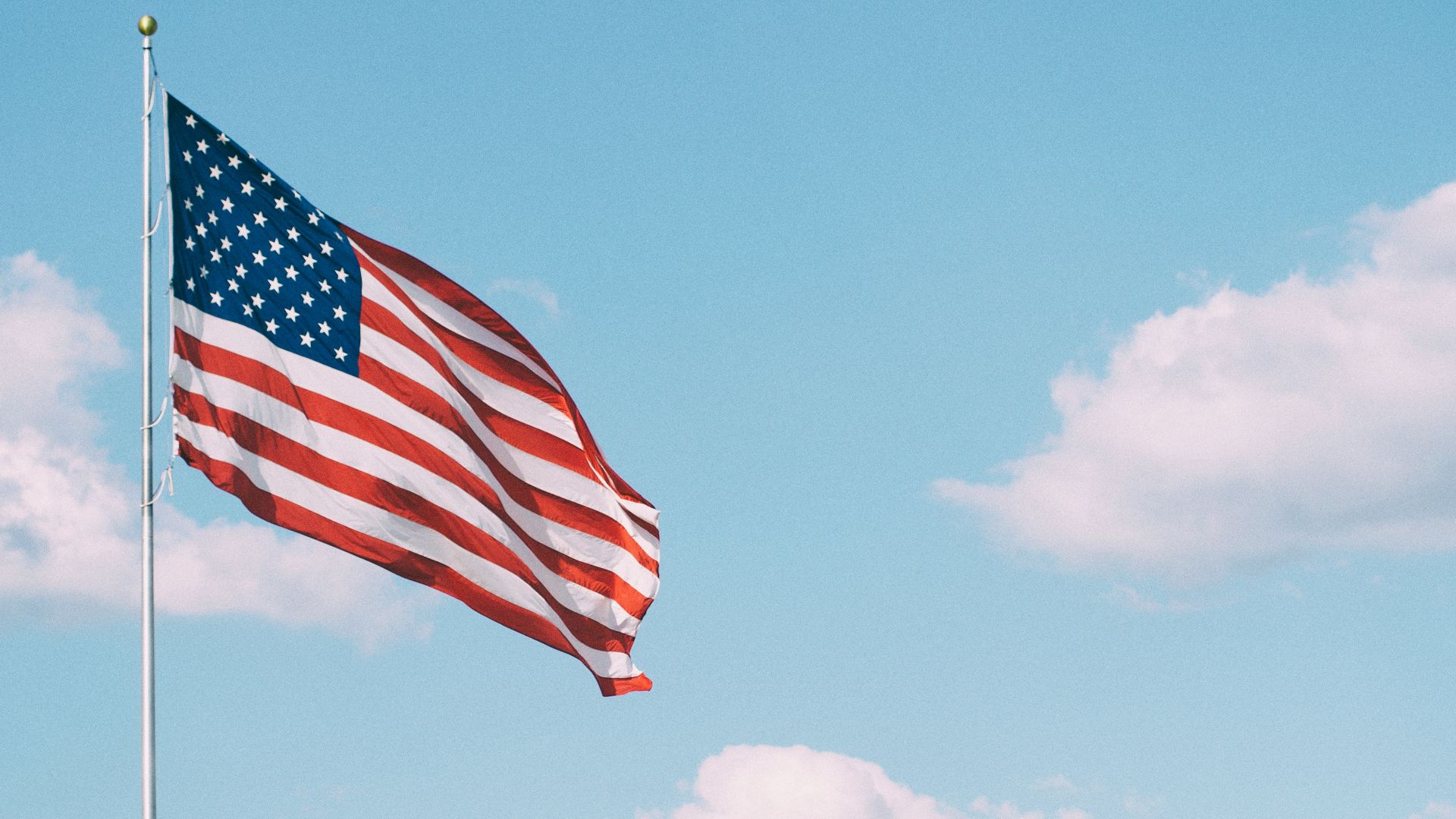 flag of U.S.A. under white clouds during daytime
