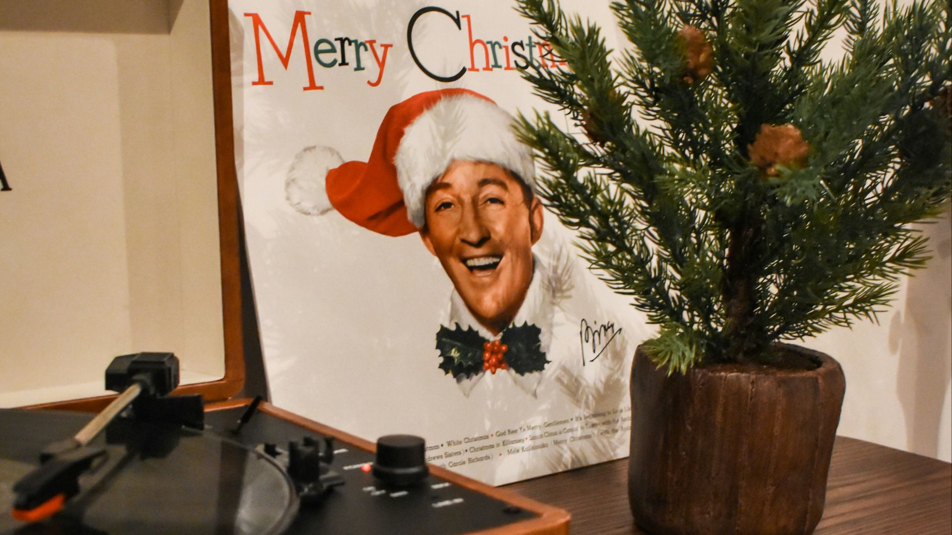 man in black suit jacket sitting beside brown wooden table
