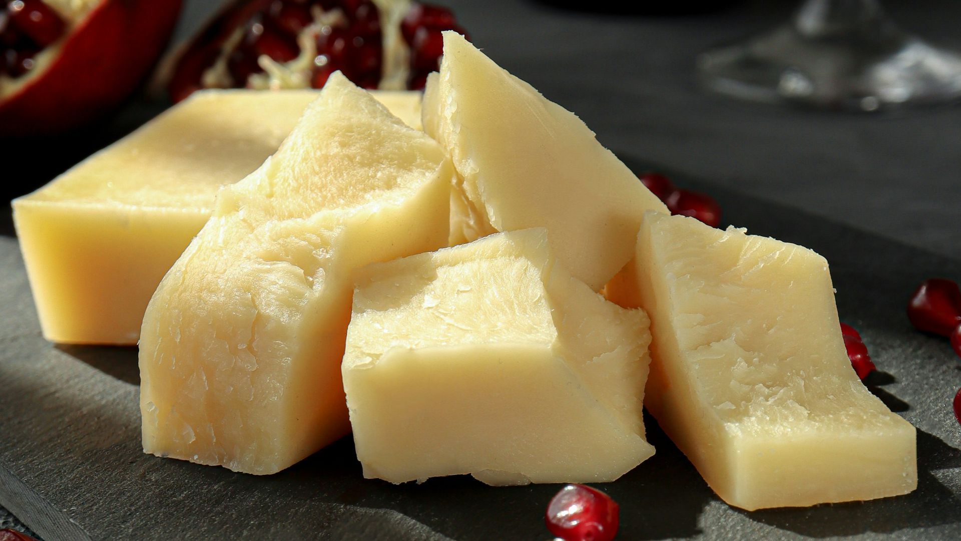 sliced cheese on black plate beside wine glass