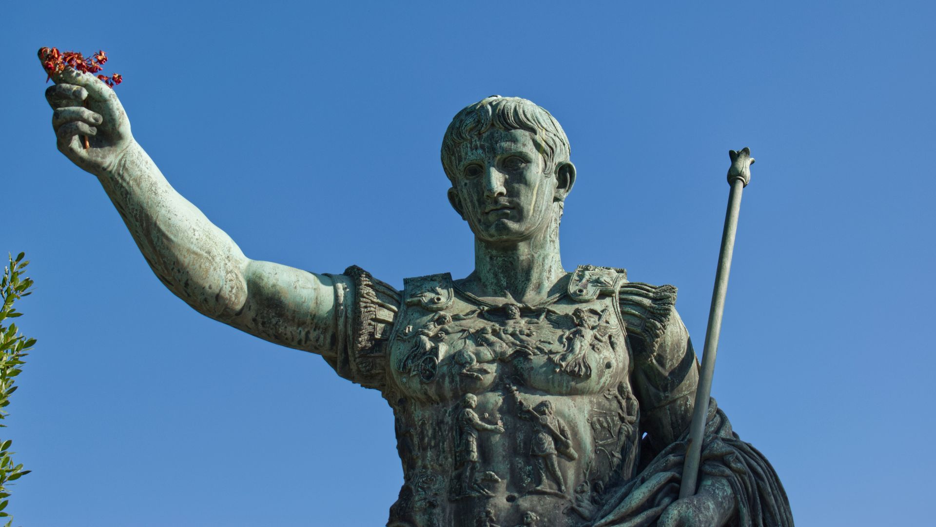 man holding stick statue under blue sky during daytime