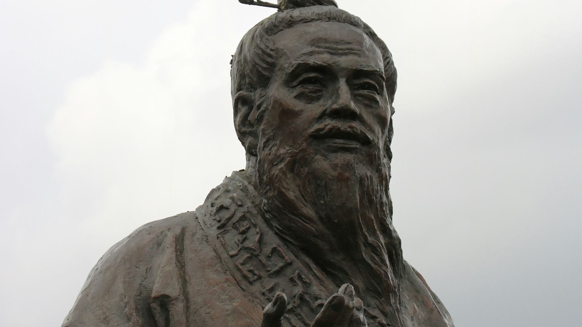 man in hat statue under white clouds during daytime