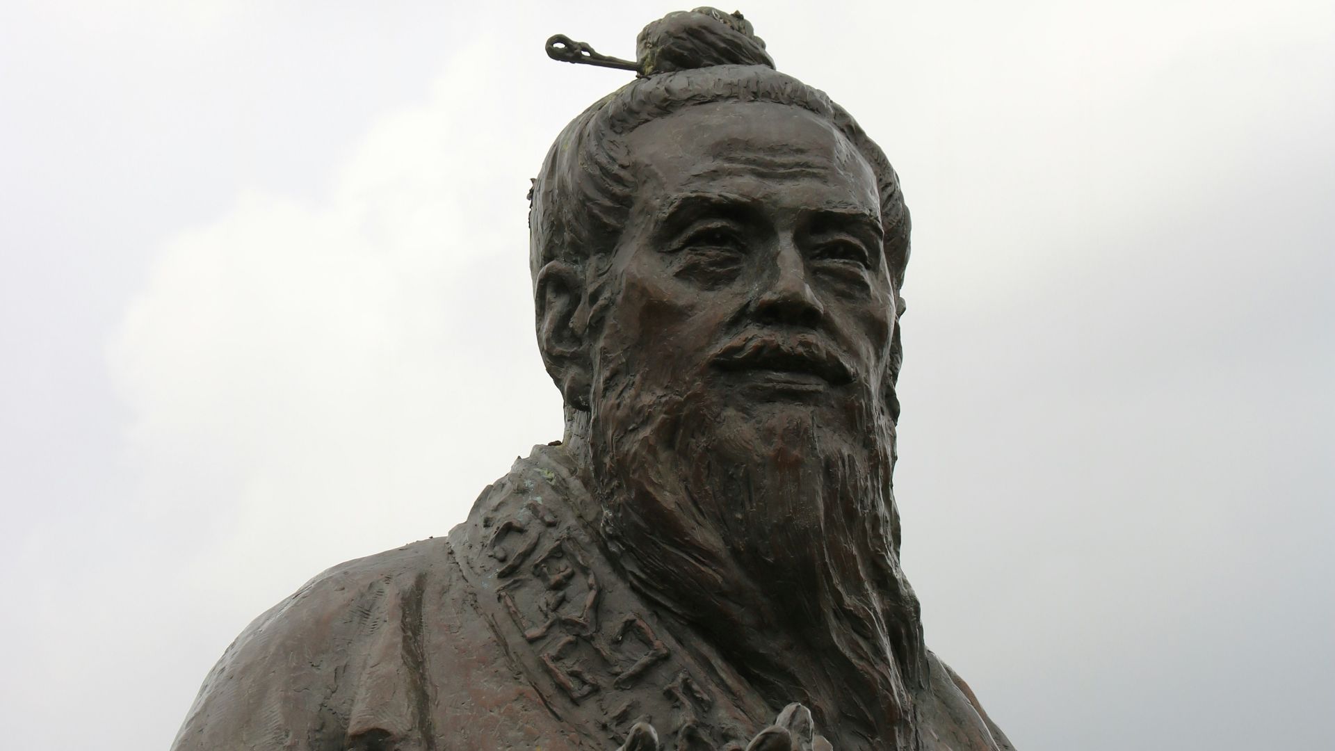 man in hat statue under white clouds during daytime