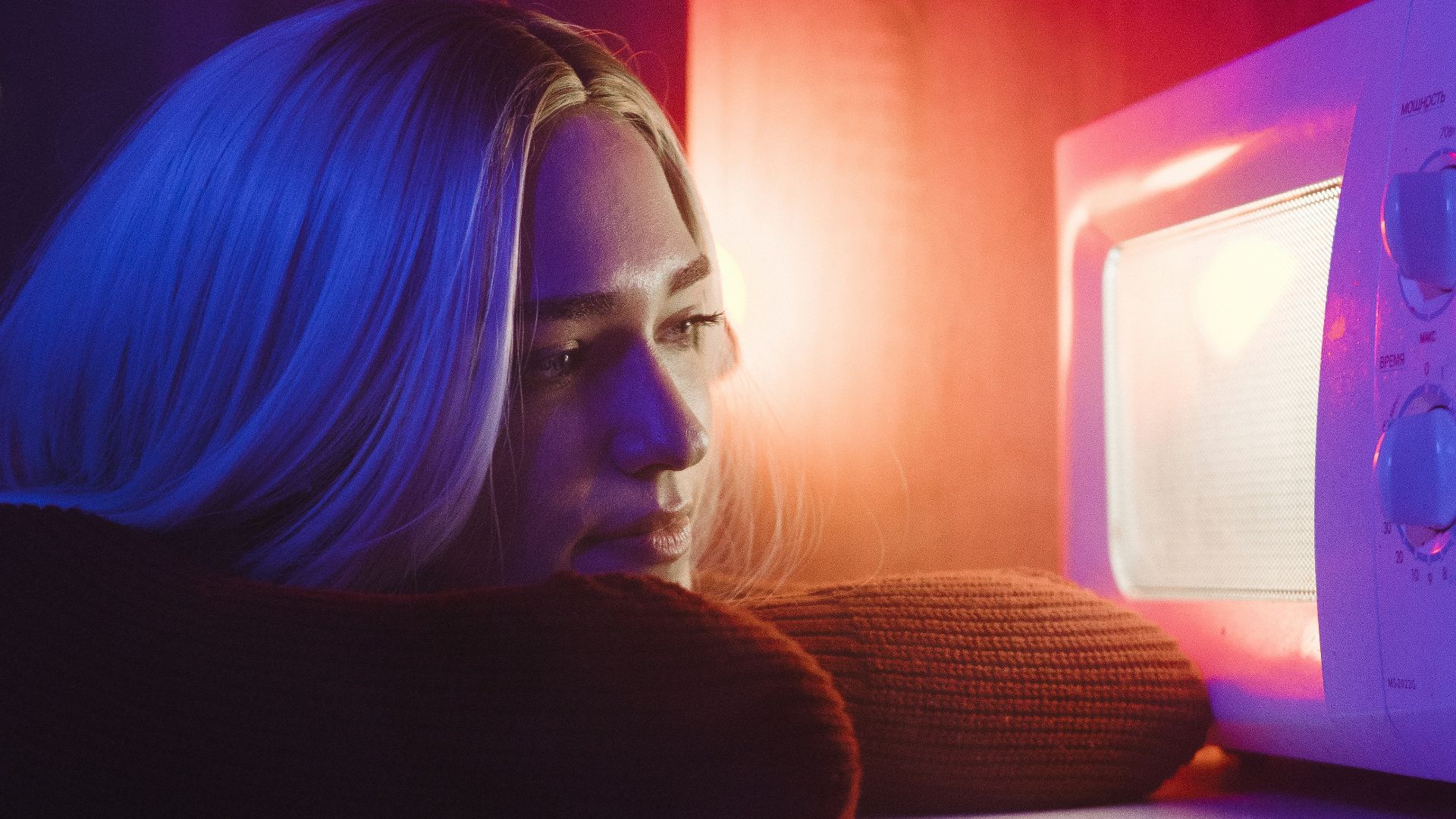 woman in black long sleeve shirt sitting beside white microwave oven