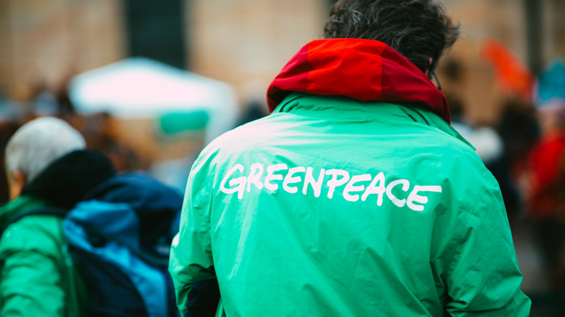 man in green hoodie walking on street during daytime