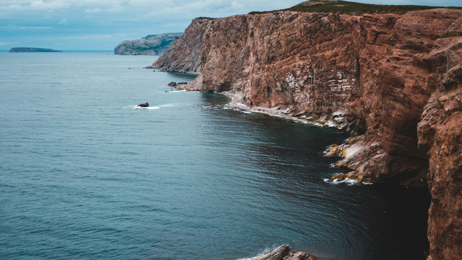 brown and green mountain beside body of water during daytime