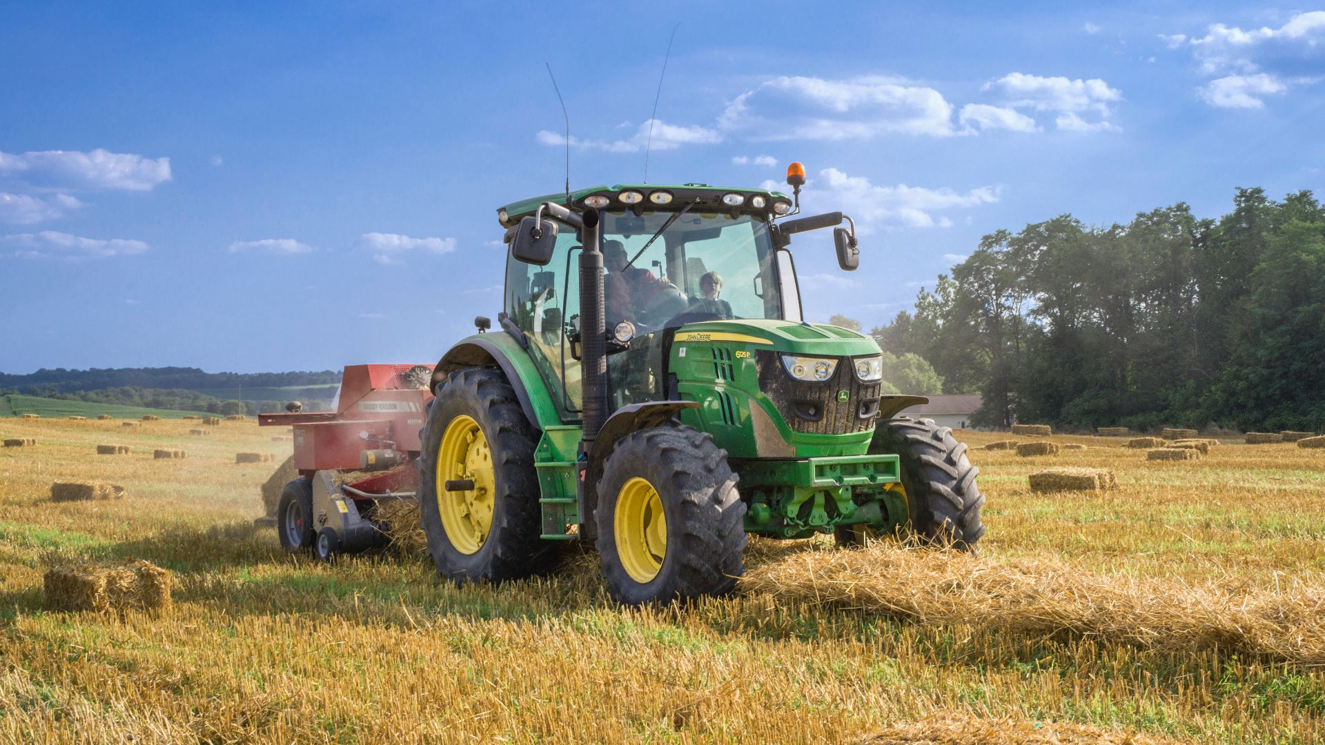 green tractor on brown grass field under blue sky during daytime
