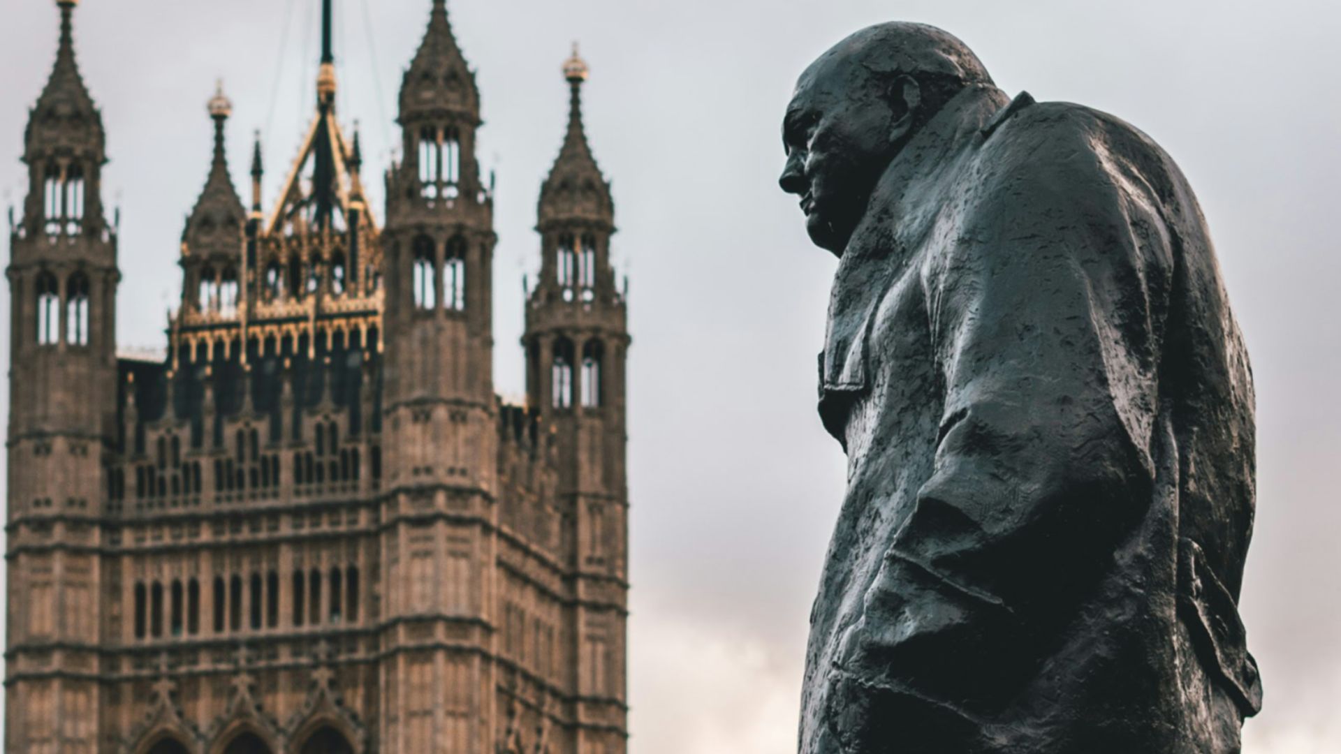 man wearing coat statue showing building with flag