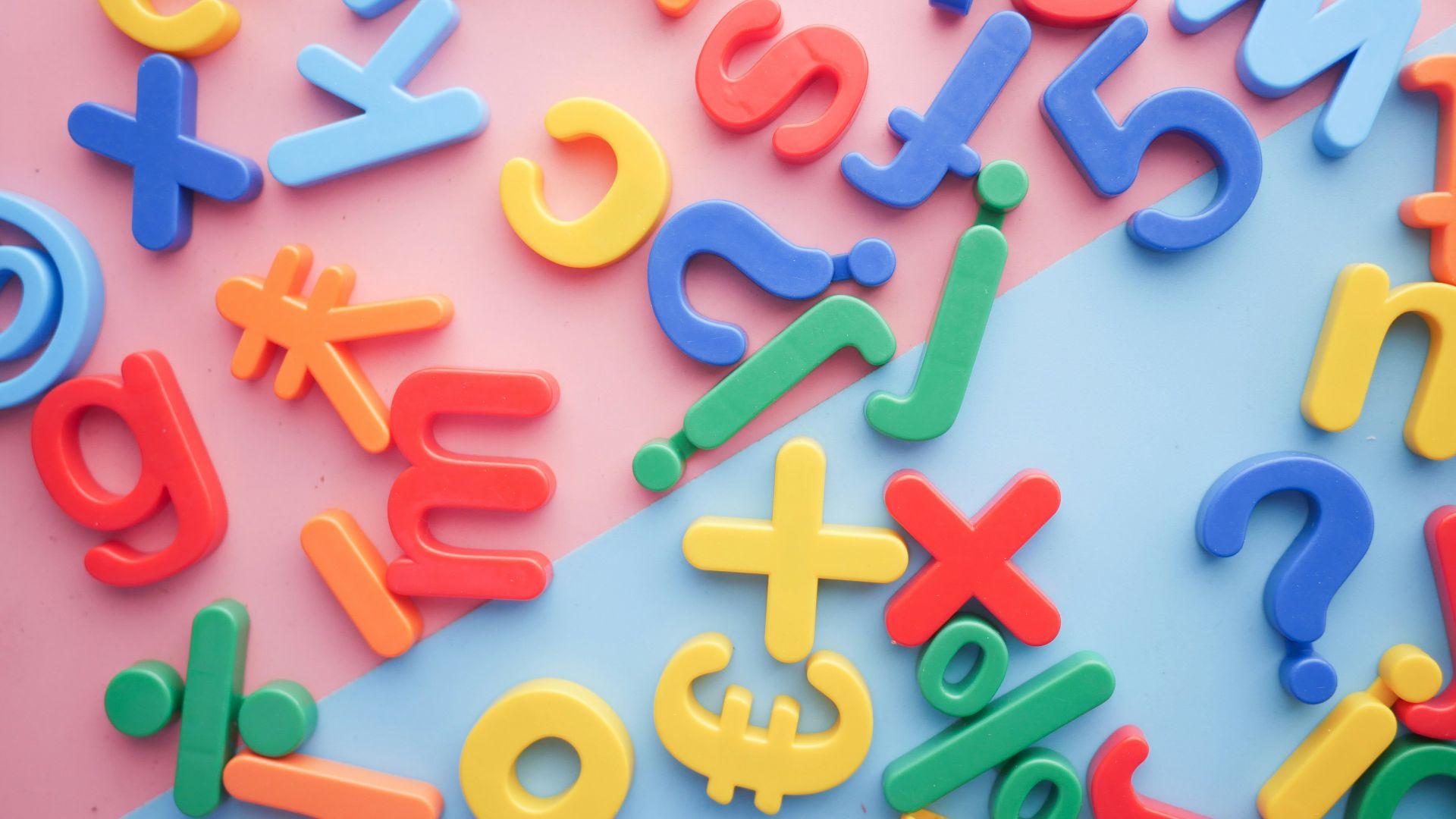 a pile of plastic letters and numbers on a pink and blue background