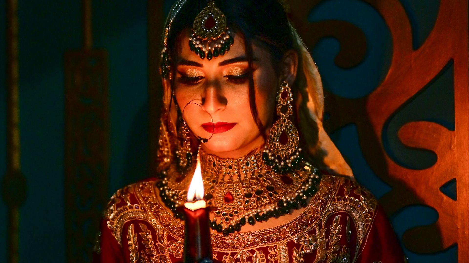 A woman in a red and gold outfit holding a candle