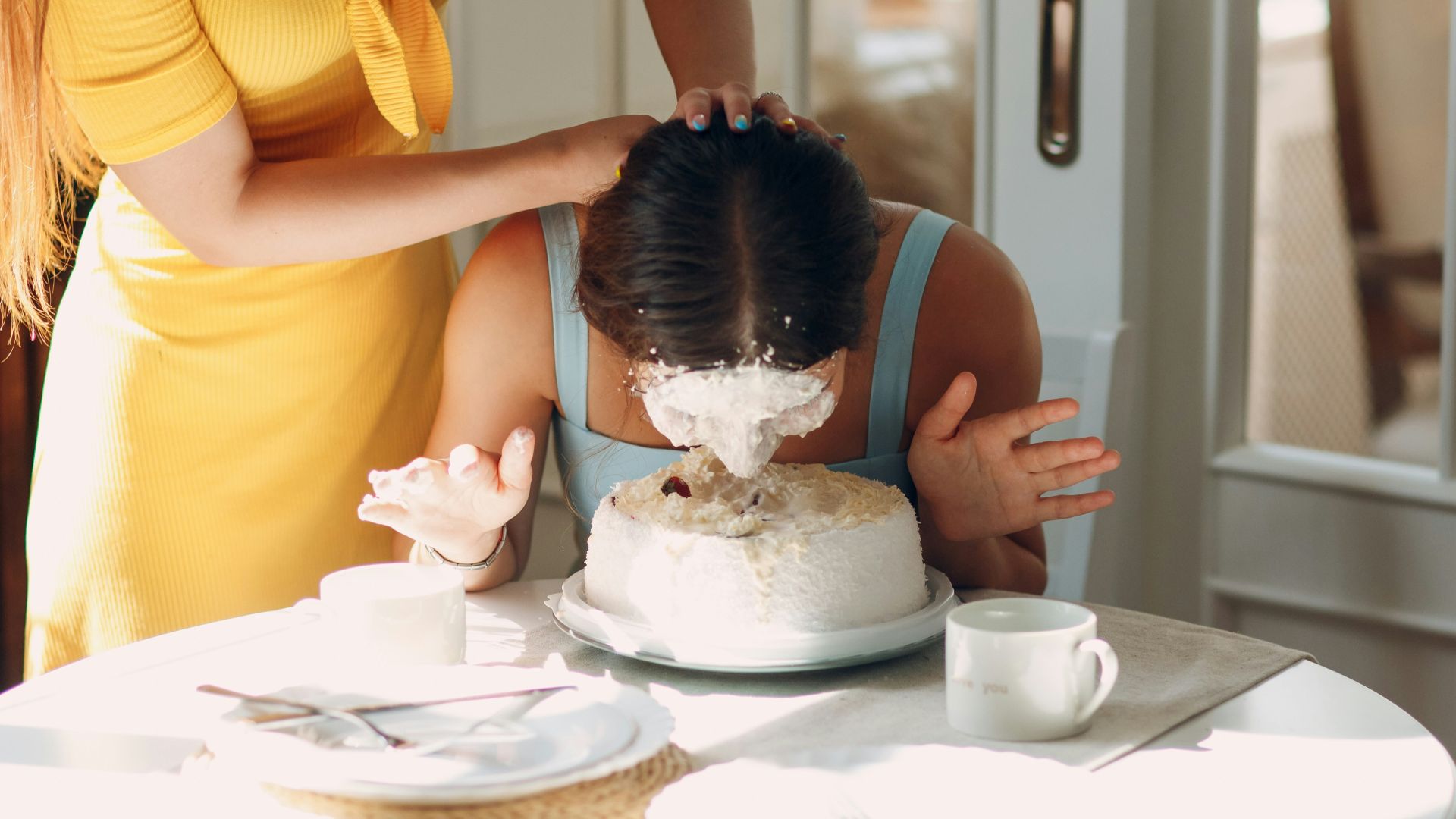 woman in yellow shirt holding girl in white dress