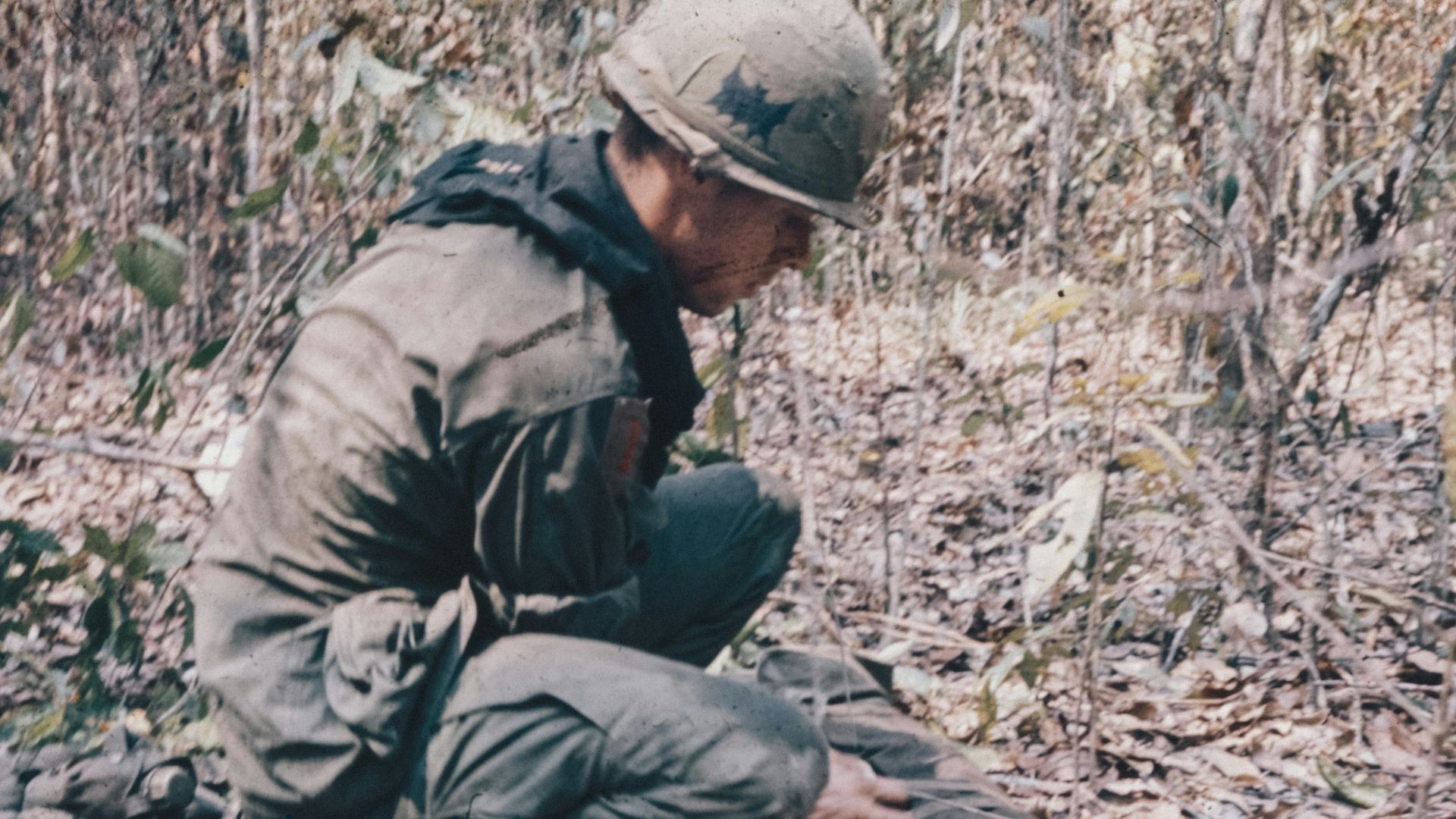 A man kneeling down next to a dead animal
