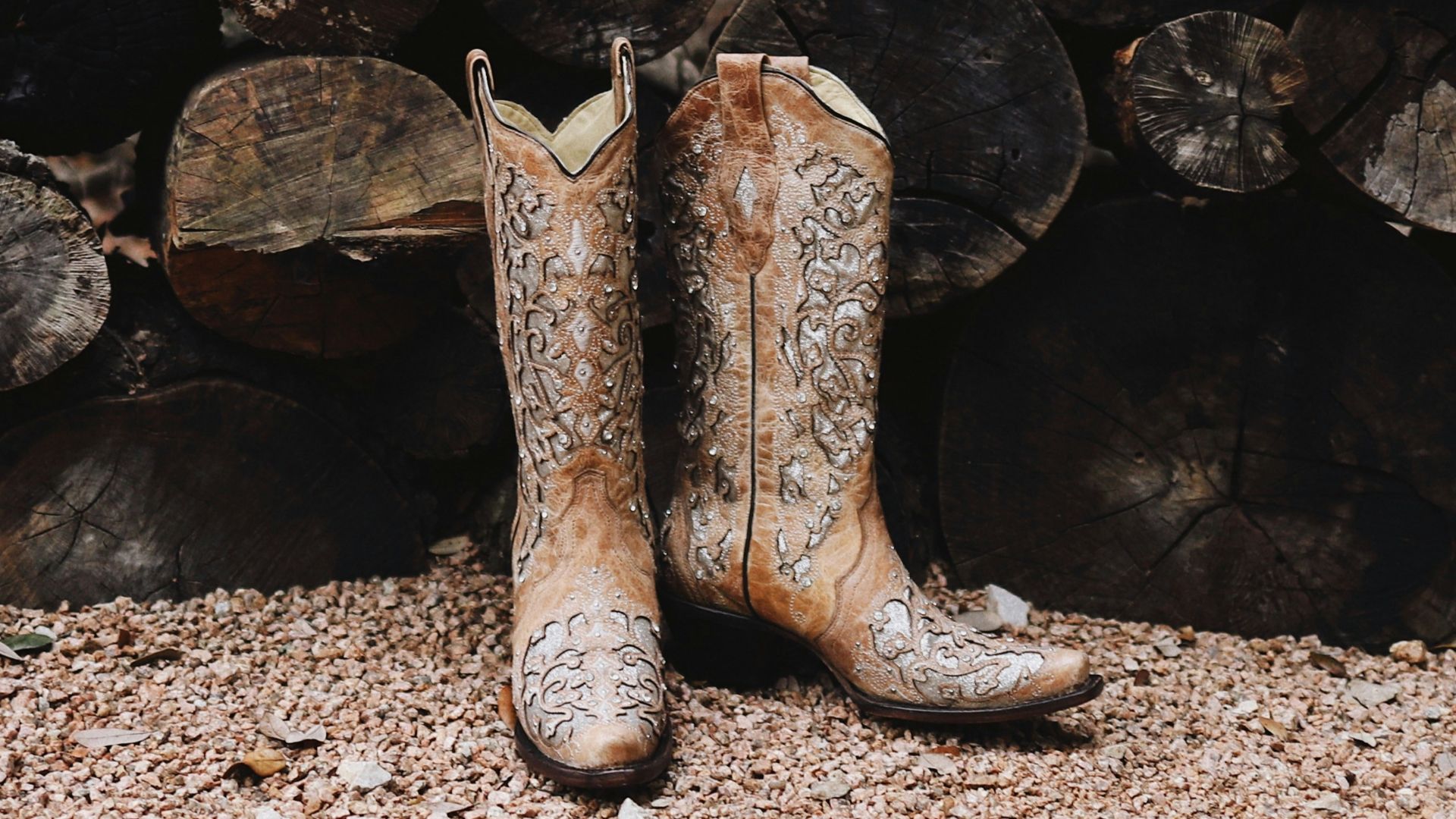 pair of brown leather cowboy boots near firewood