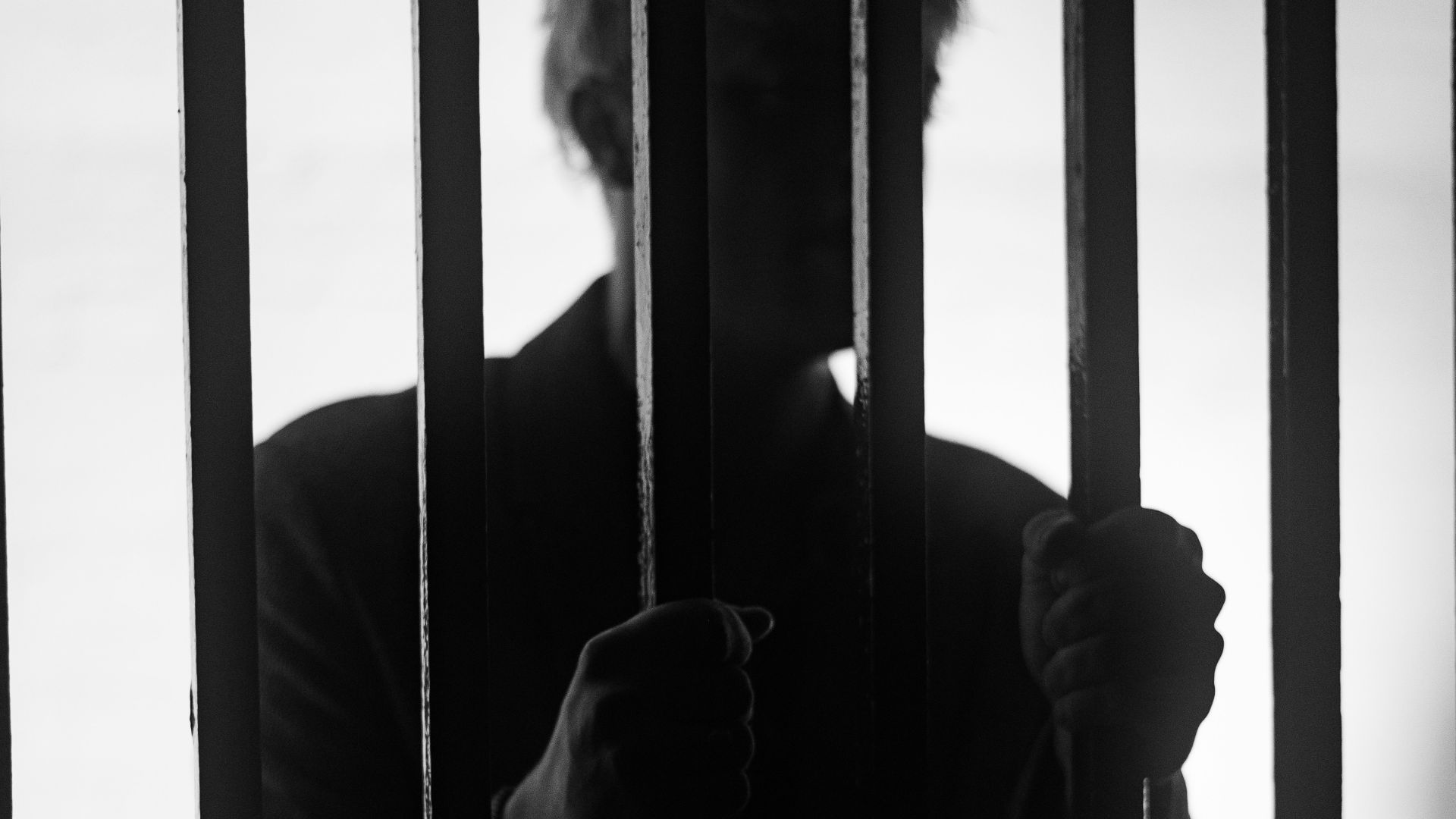 a man standing behind bars in a jail cell