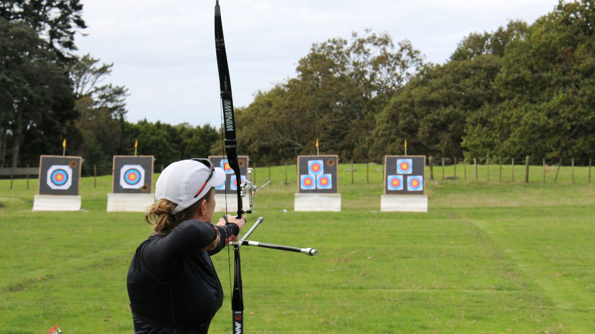 a woman is practicing archery in a field