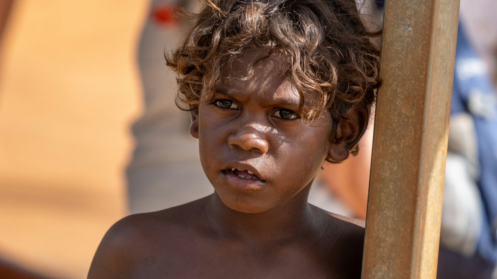 A young aboriginal boy holds a wooden pole.