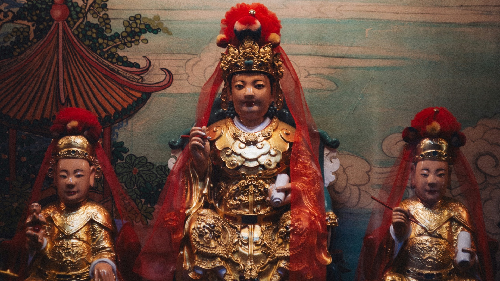 Three ornate golden statues in a shrine