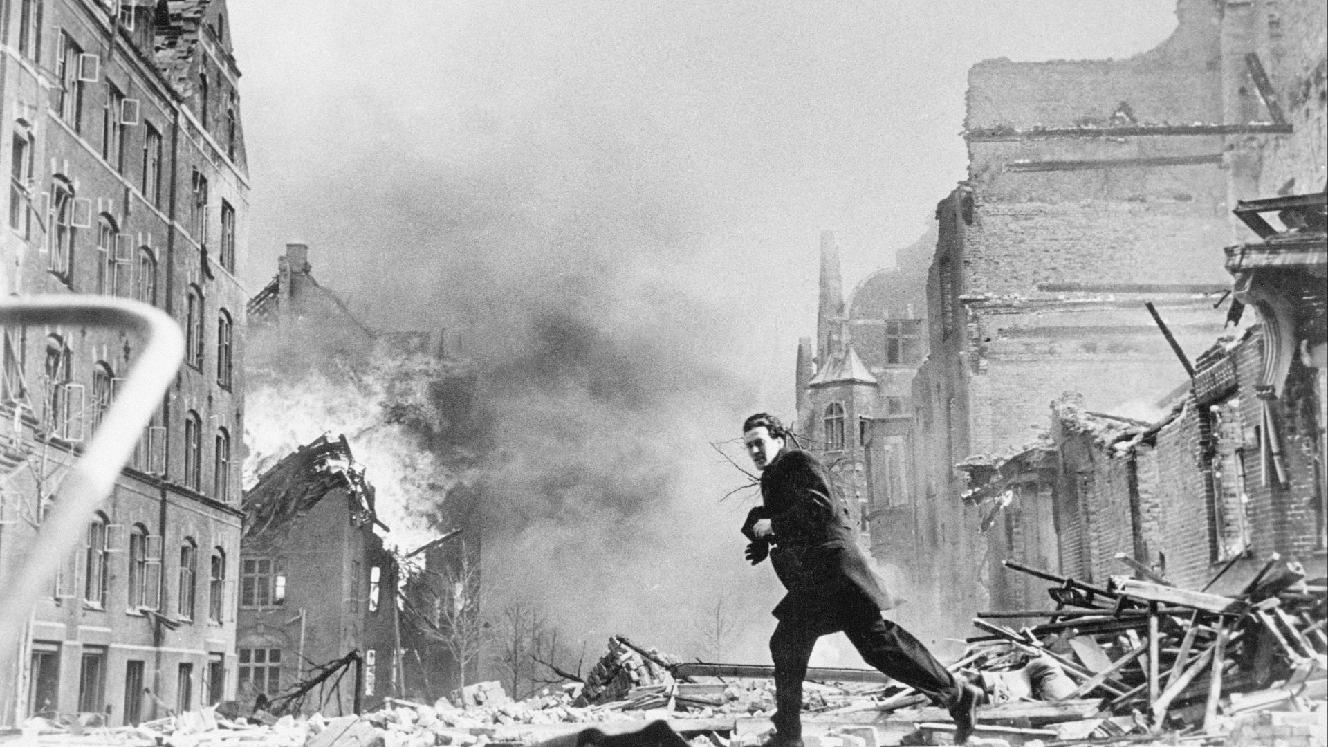 a man walking through a destroyed city street