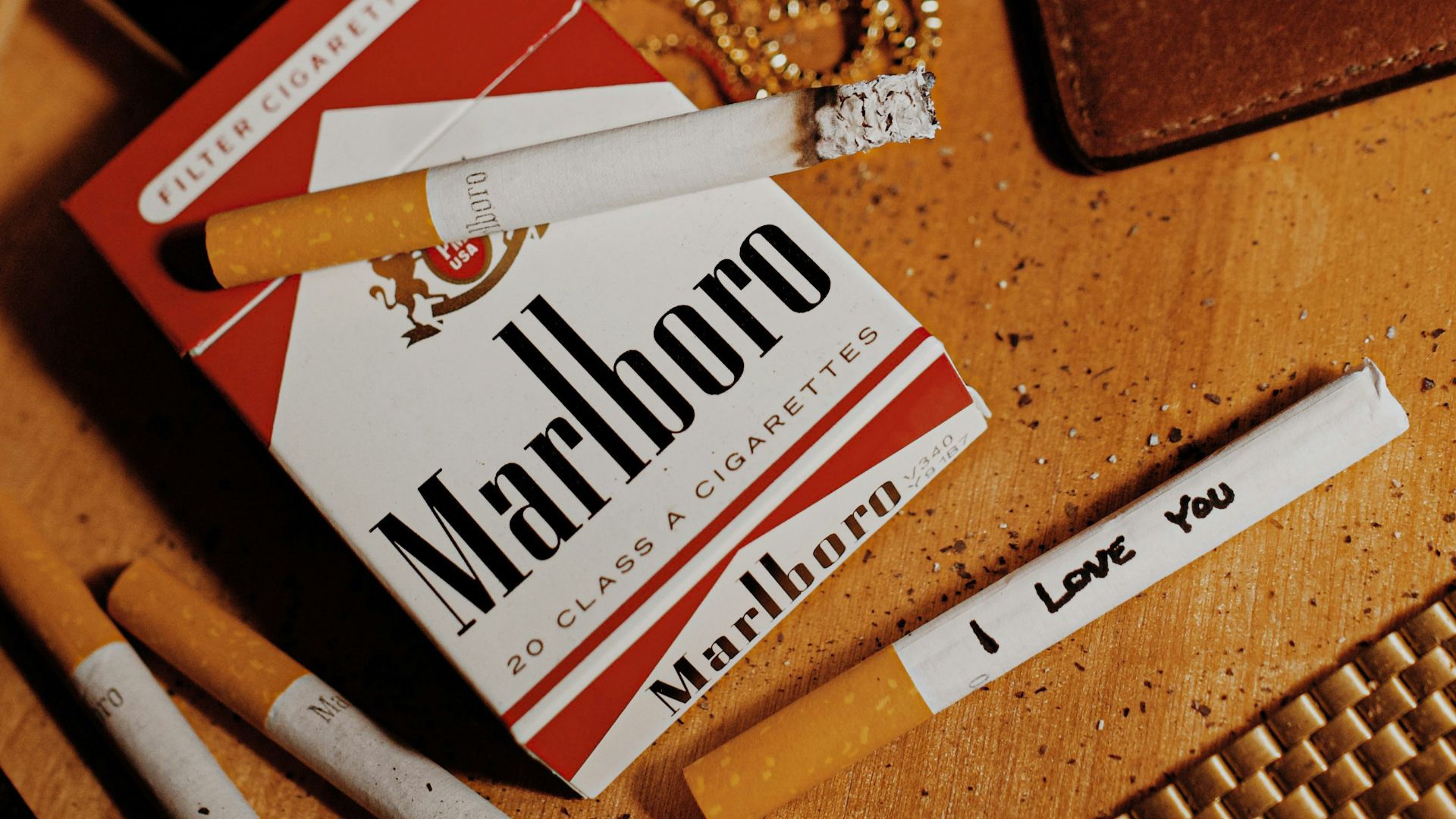 white and red marlboro cigarette pack beside brown leather bifold wallet