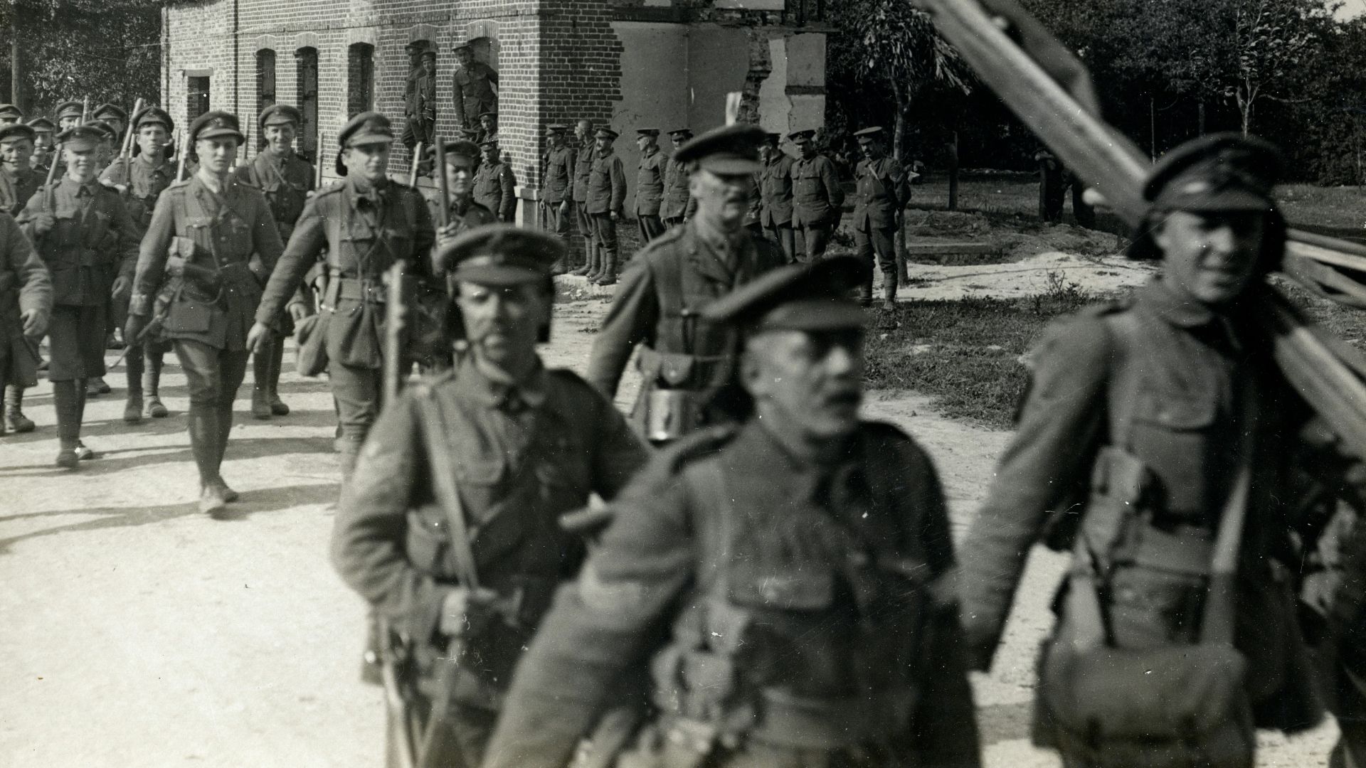 grayscale photography group of soldier walking outdoors