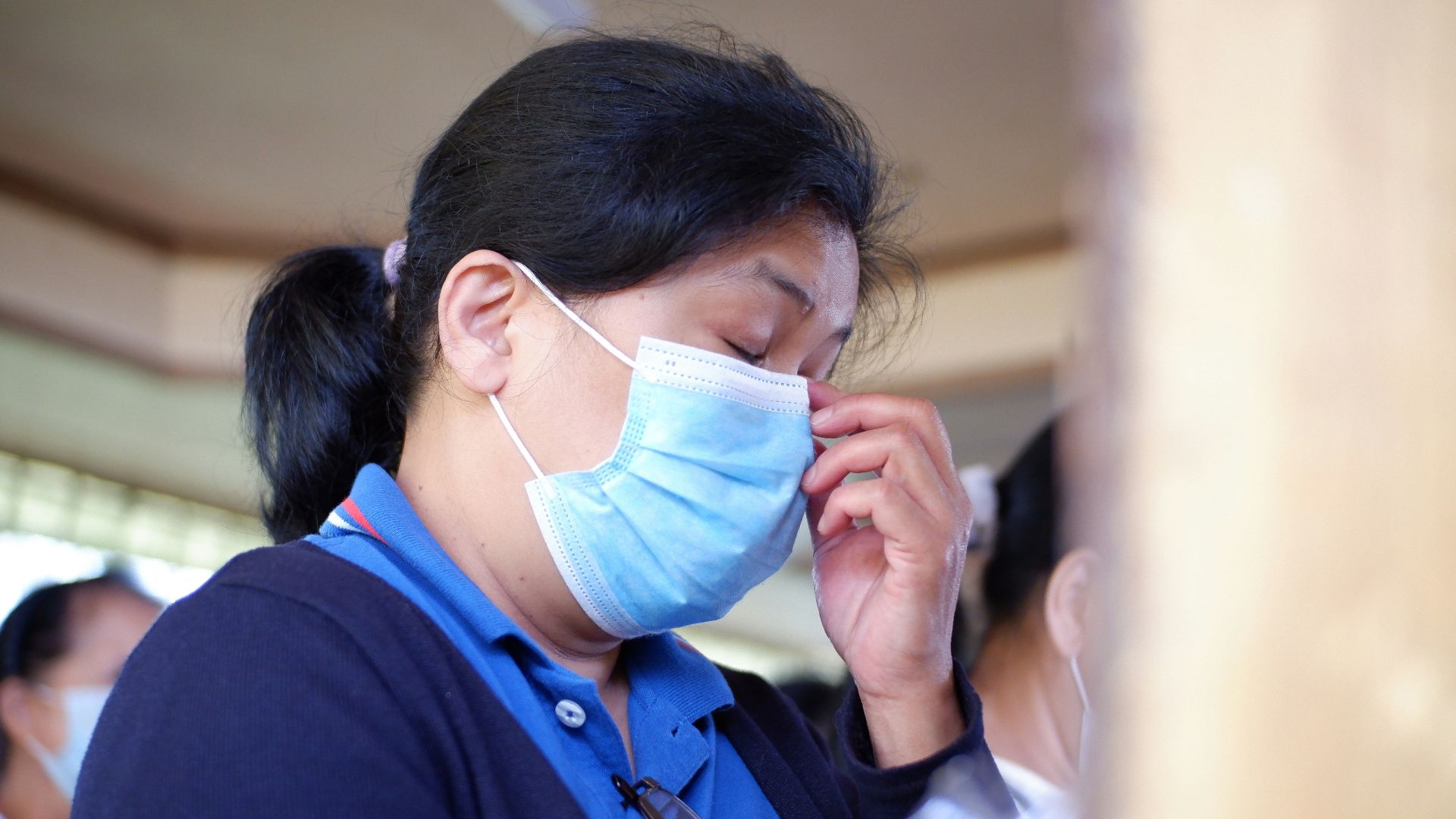 woman in blue shirt covering face with white paper