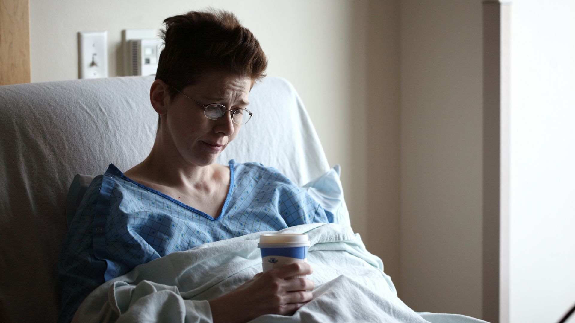woman on bed holding plastic cup