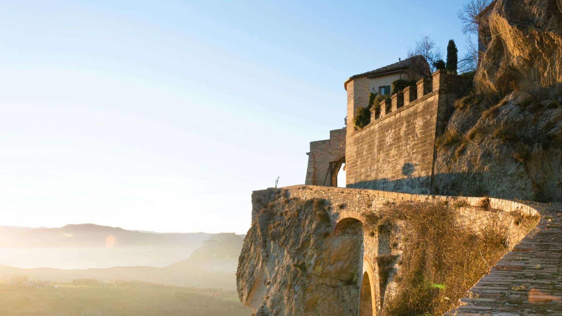 a stone walkway leading to a building on top of a mountain