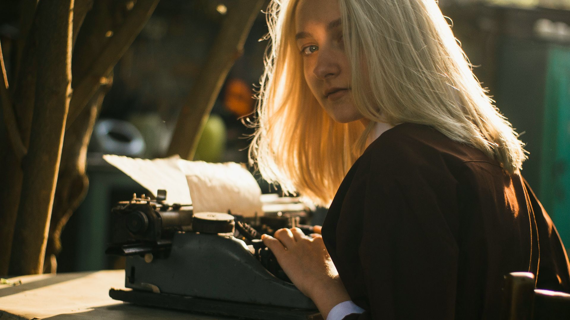 a woman sitting at a table typing on an old fashioned typewriter