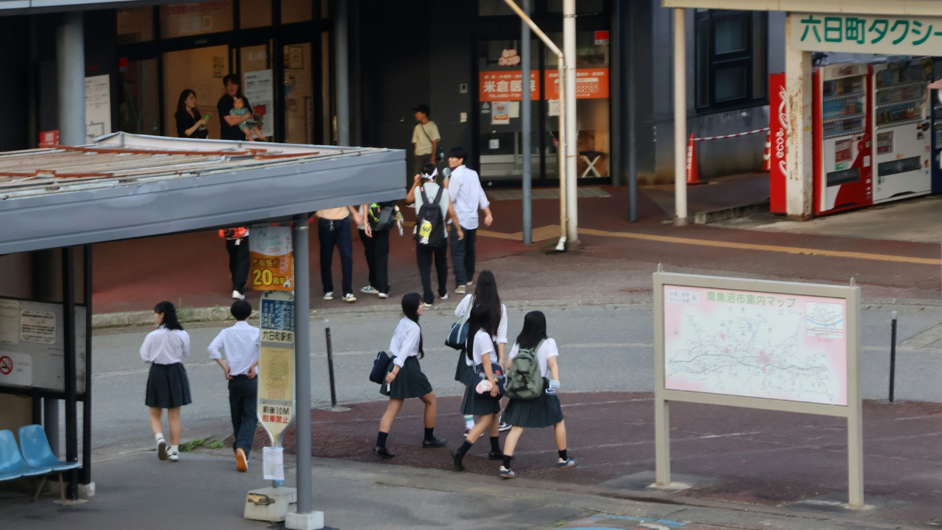 A group of people walking down a street next to a building