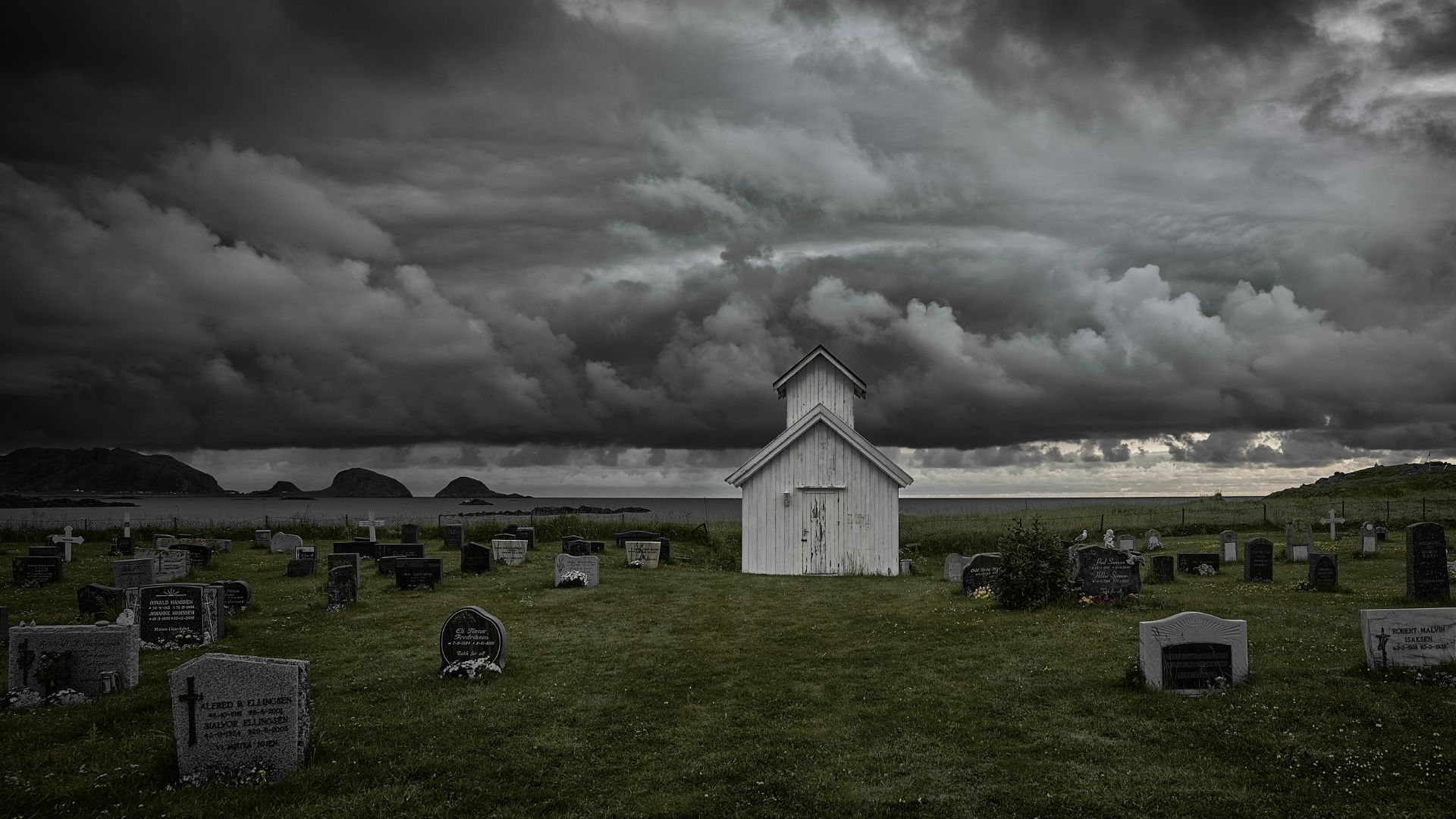 a white church in a cemetery under a cloudy sky