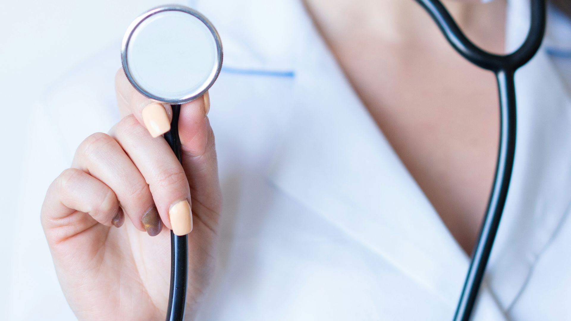a woman in a white shirt holding a stethoscope