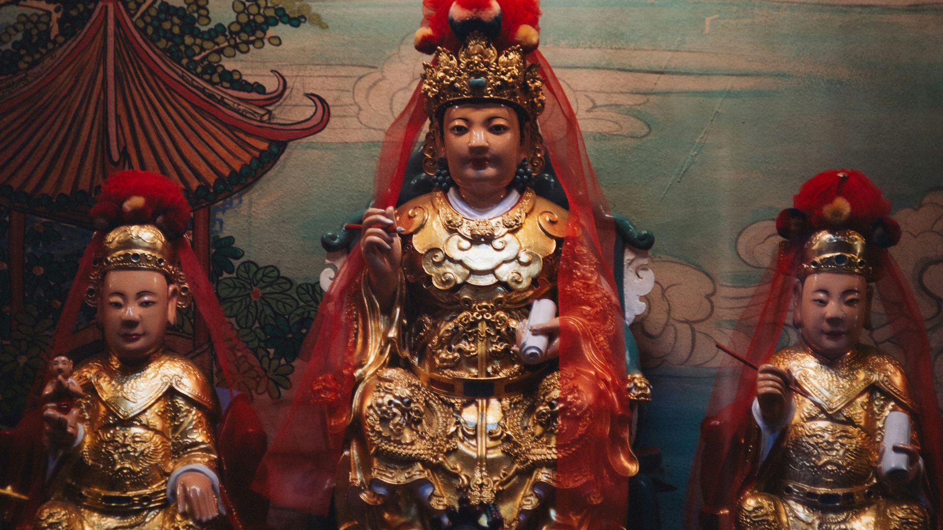 Three ornate golden statues in a shrine