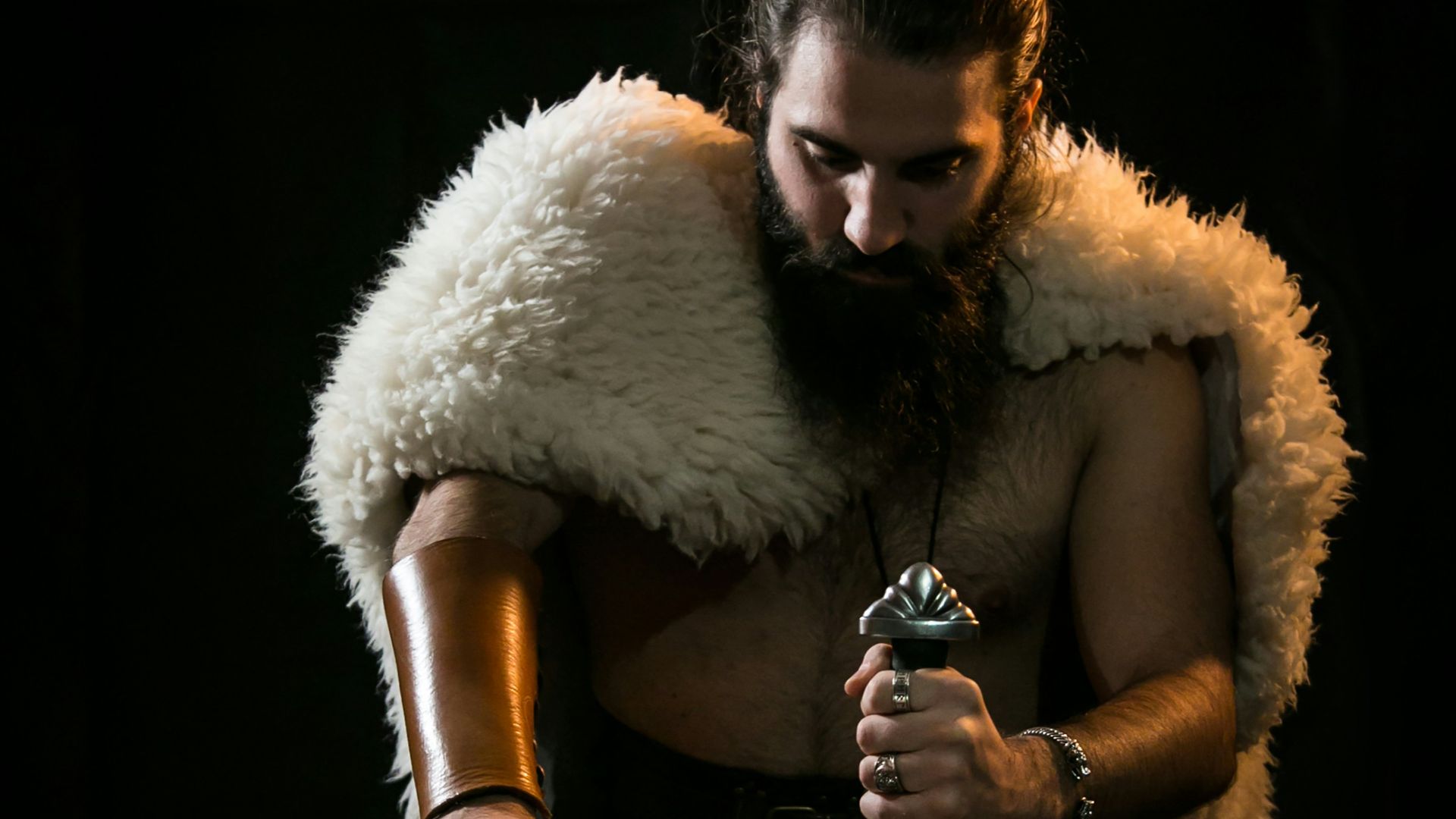 man in black pants sitting on chair holding bottle