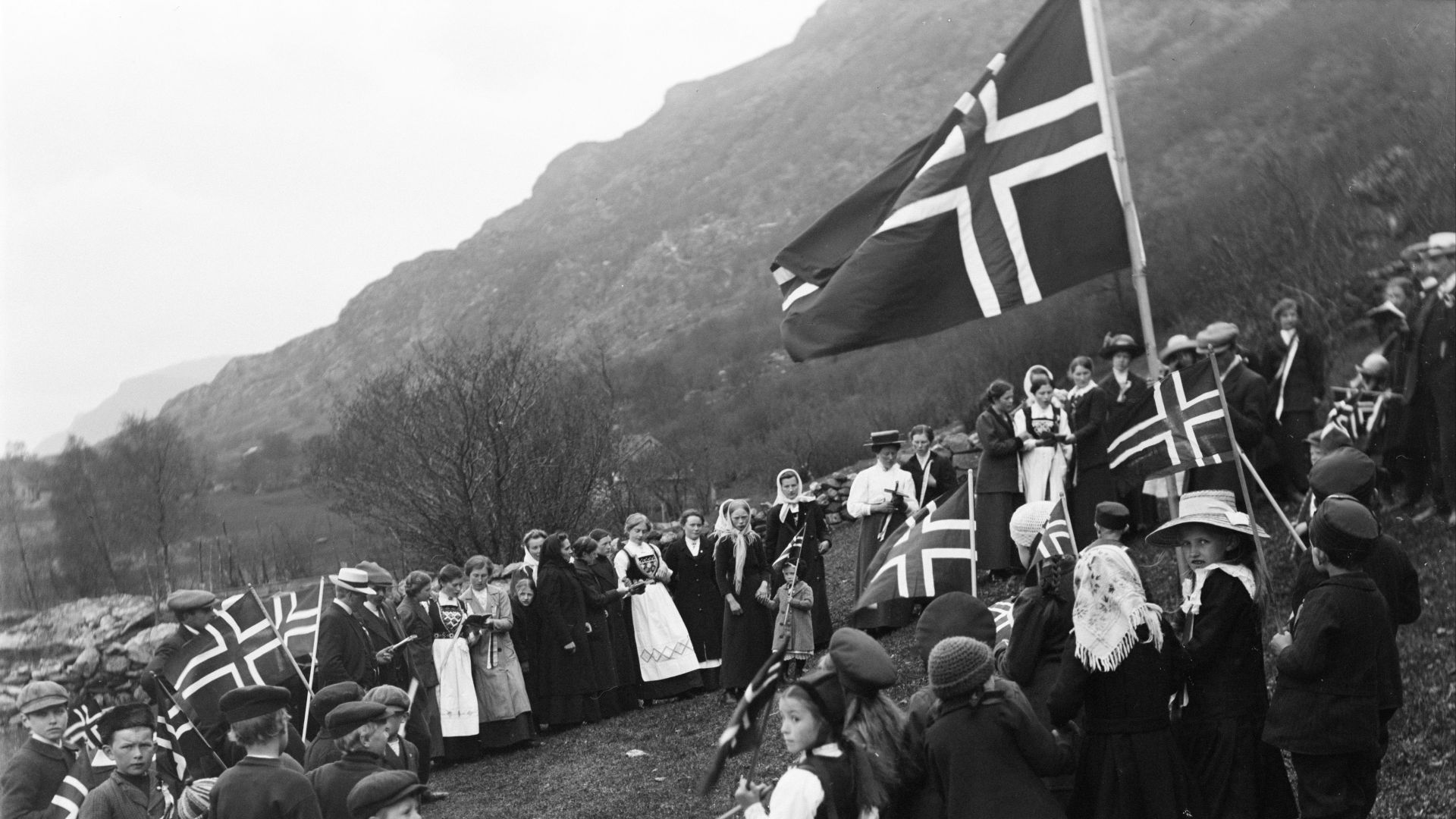People in traditional clothing holding norwegian flags
