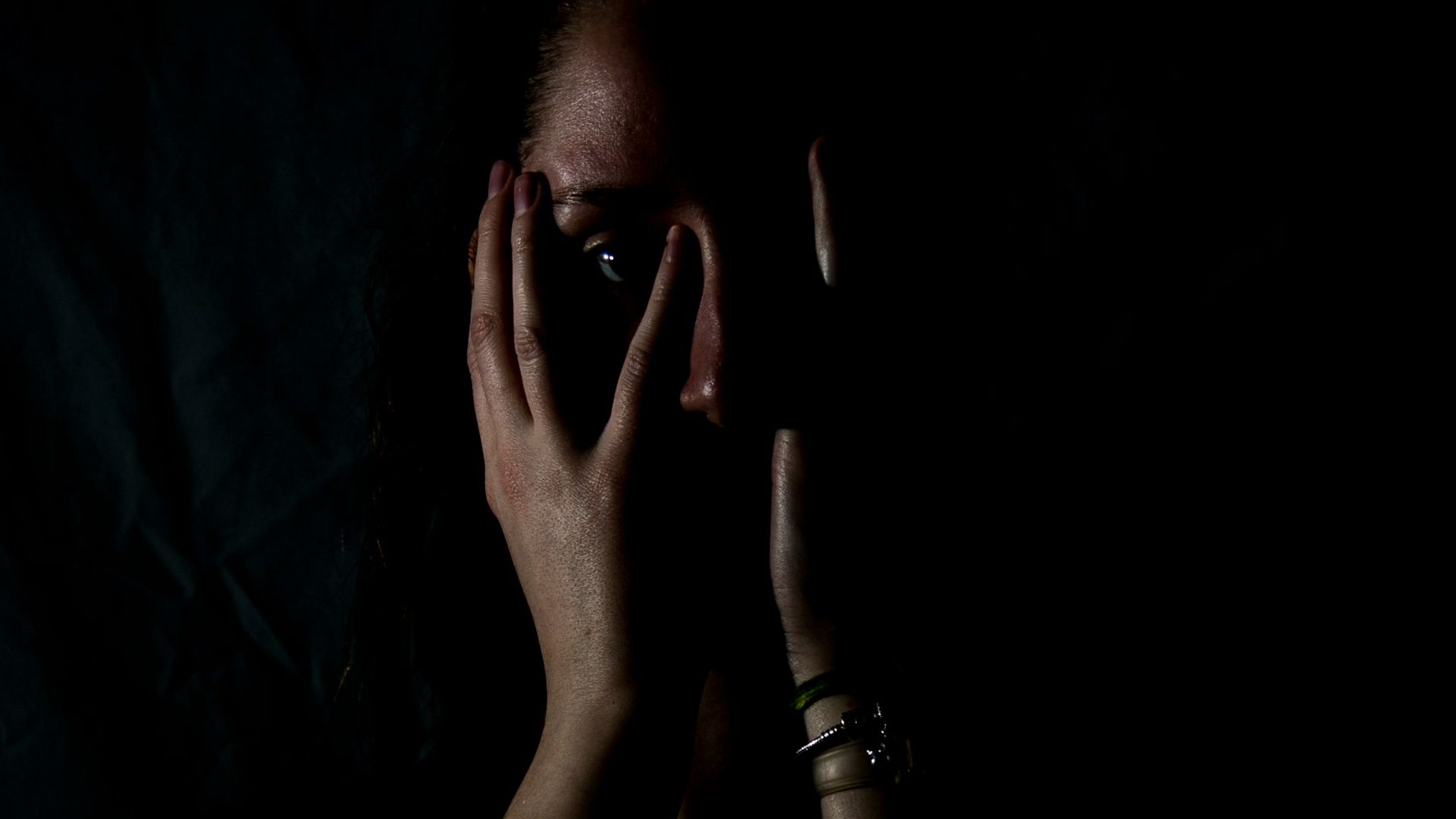 woman holding her face in dark room